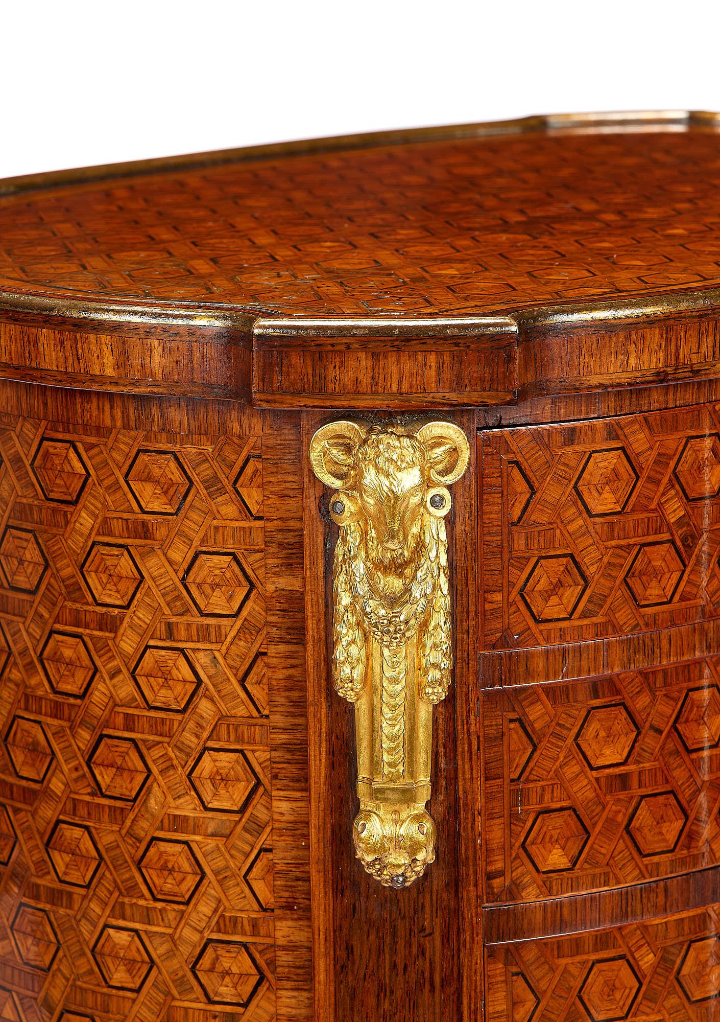 A fine late 19th century tulipwood and kingwood side table or table en chiffoniere inlaid with stained sycamore lines applied with gilt bronze mounts and an edging. The shaped oval top with projecting corners is above three drawers with gilt bronze