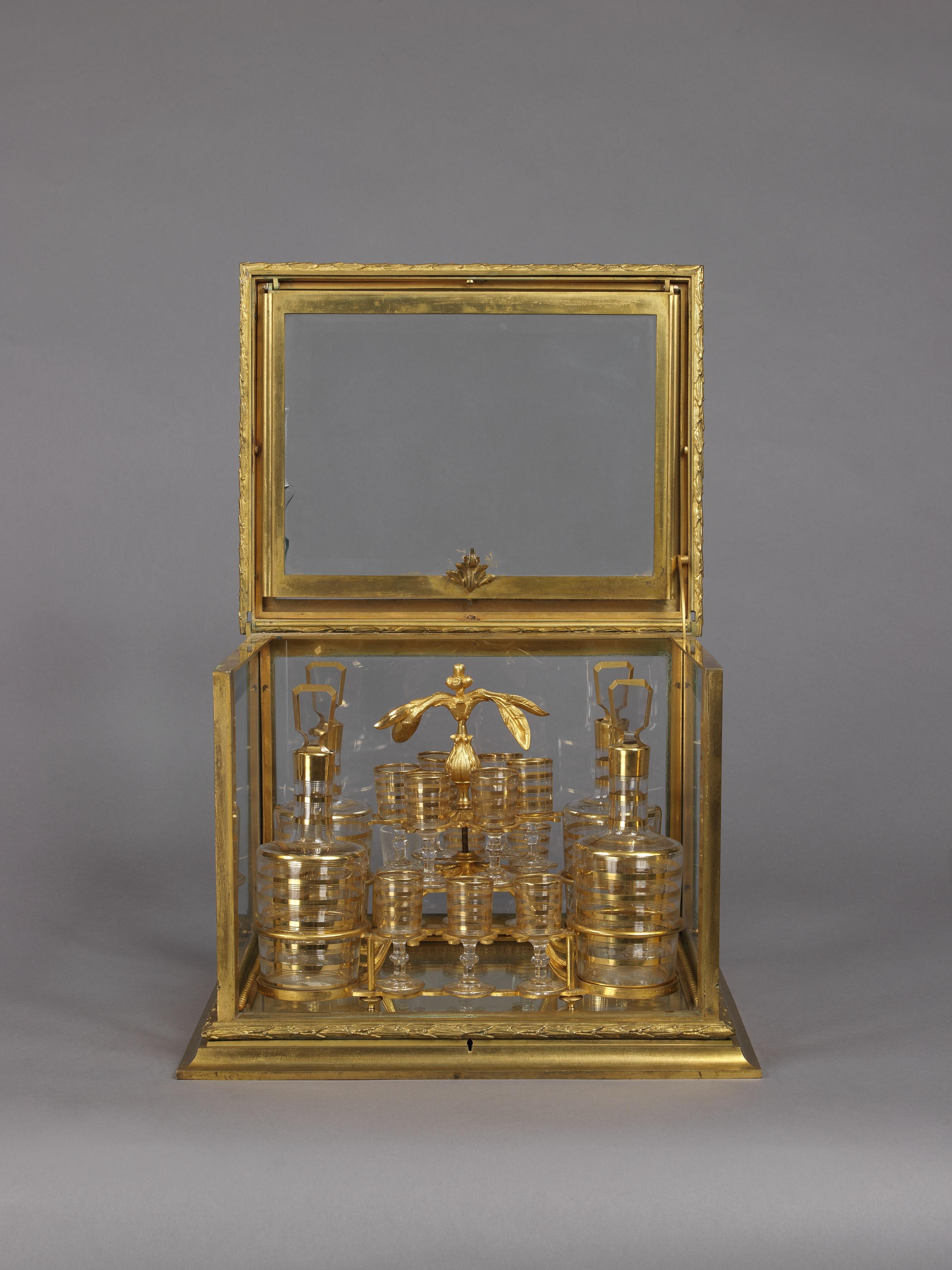 A fine and decorative gilt-bronze and cut-glass decanter set. 

French, circa 1890. 

This fine and decorative decanter set has a gilt-bronze box with glass panels and an 'up and over' lid enclosing sixteen small glasses and four decanters with
