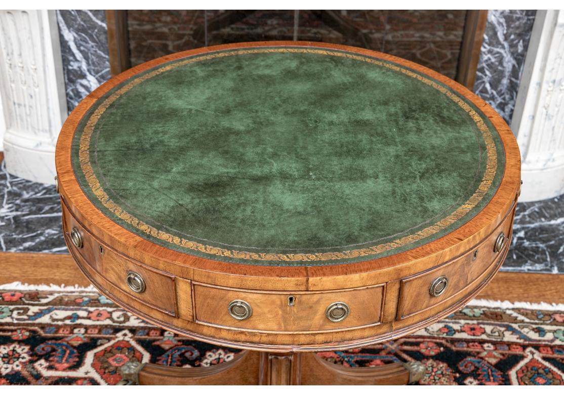 A beautifully crafted traditional Georgian Gilt-Embossed  Green Leather Drum Table. With very fine Dove-Tailed drawers (Four are real and four are faux) and having delicate Brass Ring Pulls and inset brass Key Escutcheons. The wood is handsome and