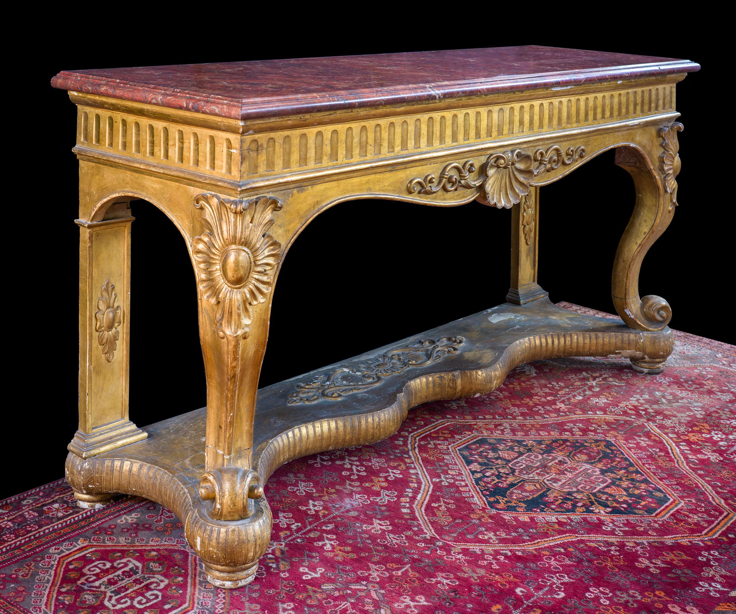 A fine and large giltwood Italian console or game table. The substantial rouge royale marble top is supported by a fluted frieze on a serpentine frame, centred by a scallop shell on snail feet over an unusual serpentine stretcher.

Italian, c.1820.