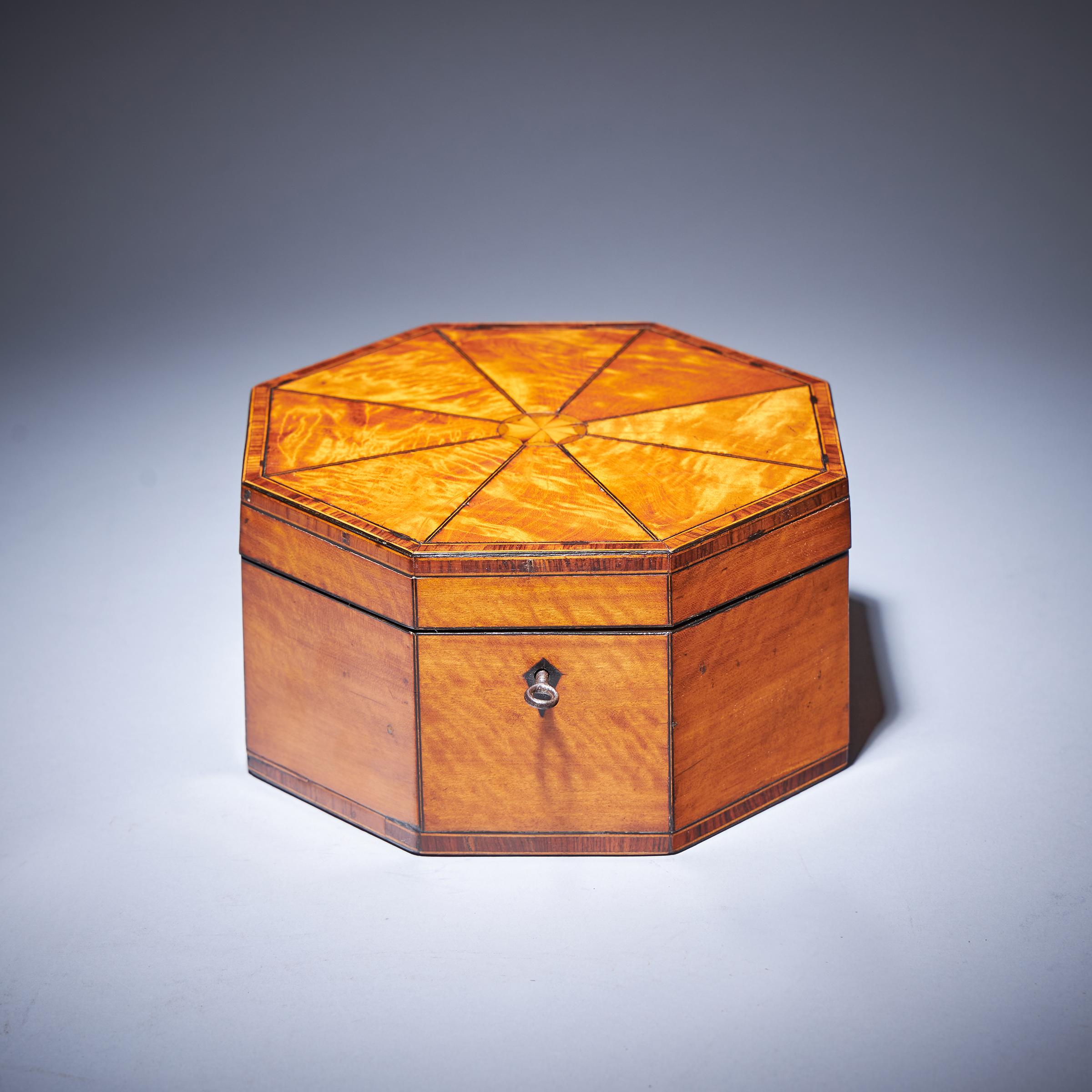 A Fine and Rare Late 18th Century George III Satinwood Octagonal Box, C.1790.
 
The kingwood crossbanded sectional top with ebony and box stringing is finely laid around a central inlaid patera. Opening on double hinges to the ebony lipped satinwood