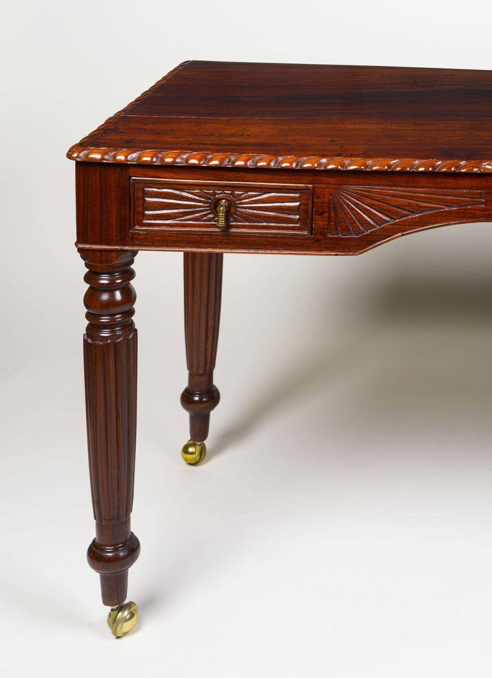 19th Century

The solid rectangular top with carved gadrooned edge; over two frieze drawers with drop handles flanking an arched kneehole ,rope detail and further linear, raised on boldly turned and reeds legs on casters.
