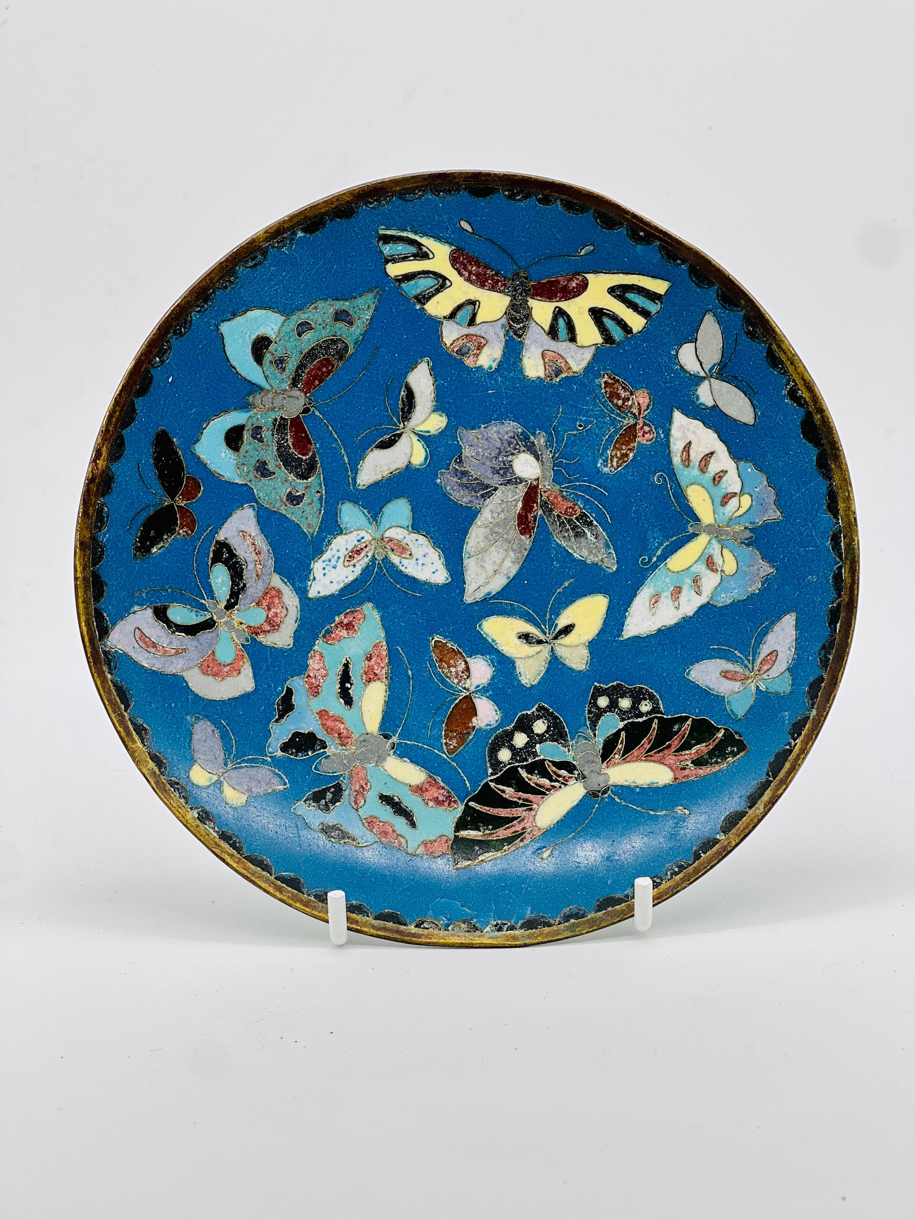 A fine Antique Japanese Cloisonne enamel butterfly Plate. Meiji Period.


Worked in silver wire of varying gauge with many colorful butterflies, reserved on a blue ground. The bottom with a pale green enamel.


Size: 15 cm in