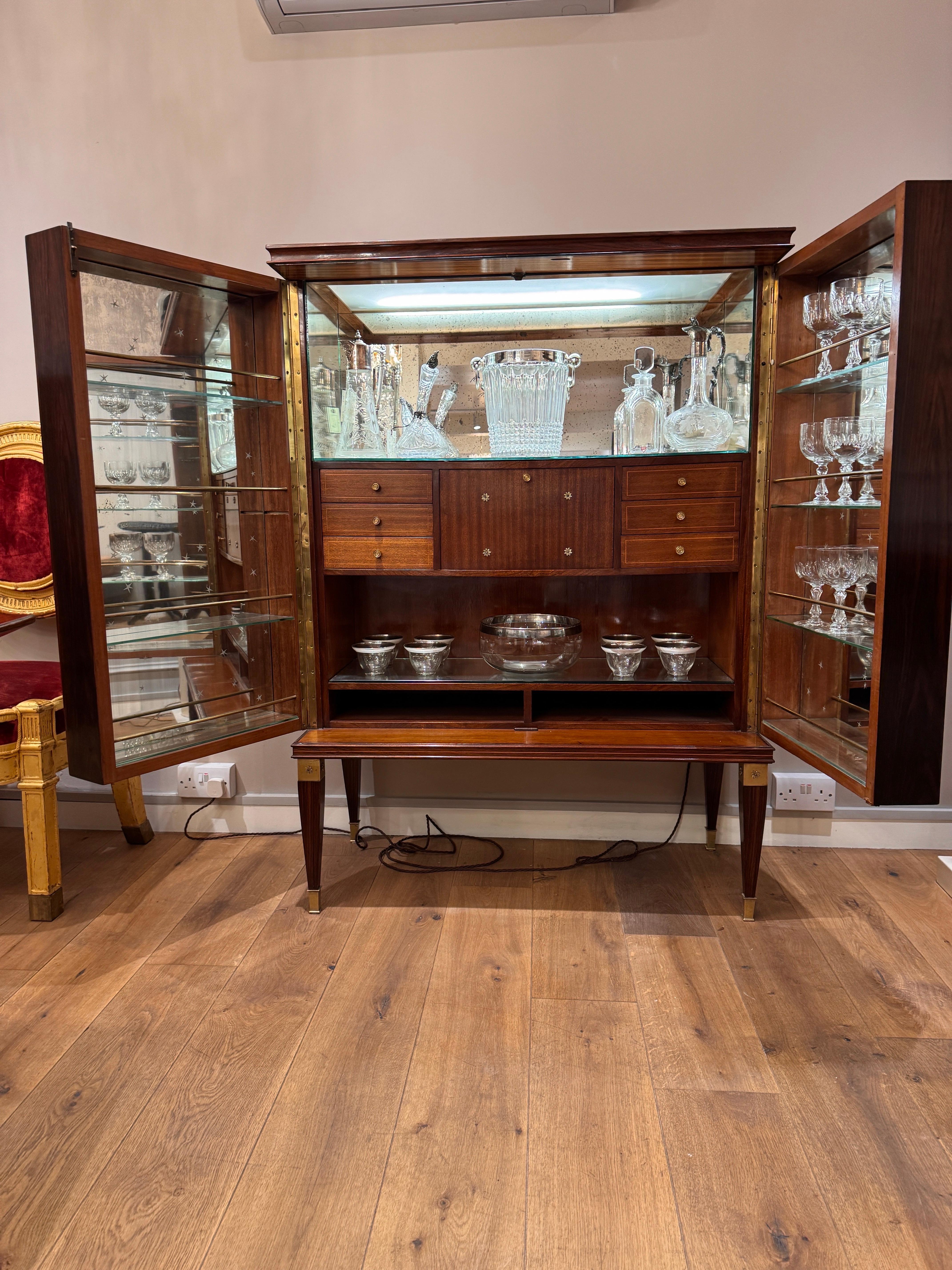 Mobile bar indipendente in mogano italiano degli anni '50, restaurato di recente da Paolo Buffa. Le ante contrapposte rivelano un interno illuminato quando vengono aperte, con cassetti a intarsio e pareti originali a specchio. Le porte anteriori