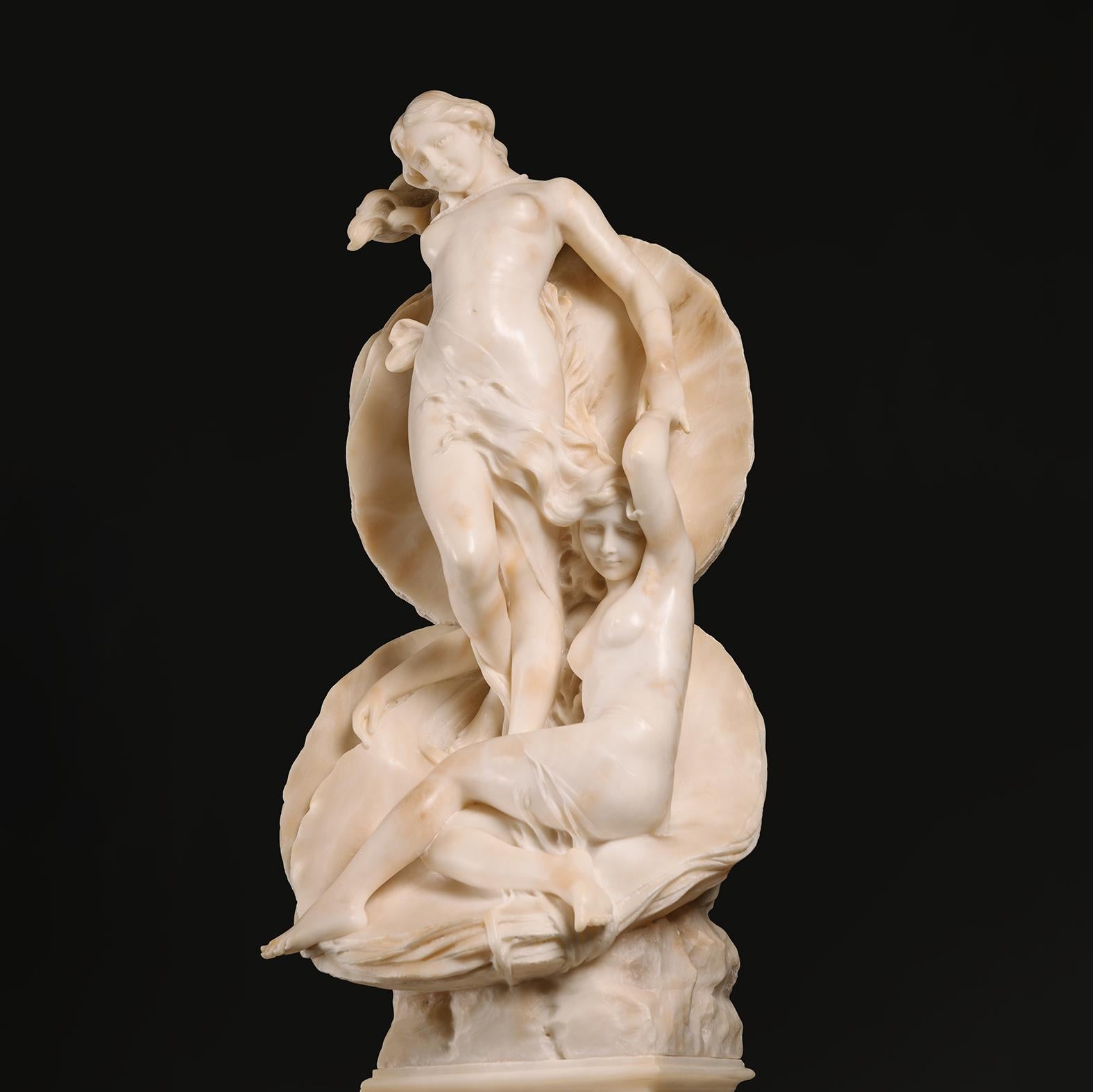 Fino grupo de alabastro tallado de El nacimiento de Venus, sobre pedestal.  

Venus, de pie sobre una concha de ostra abierta, sostiene la mano de una ninfa sentada a sus pies. Sobre pedestal de alabastro veteado.

Italia, circa 1900.

El Nacimiento
