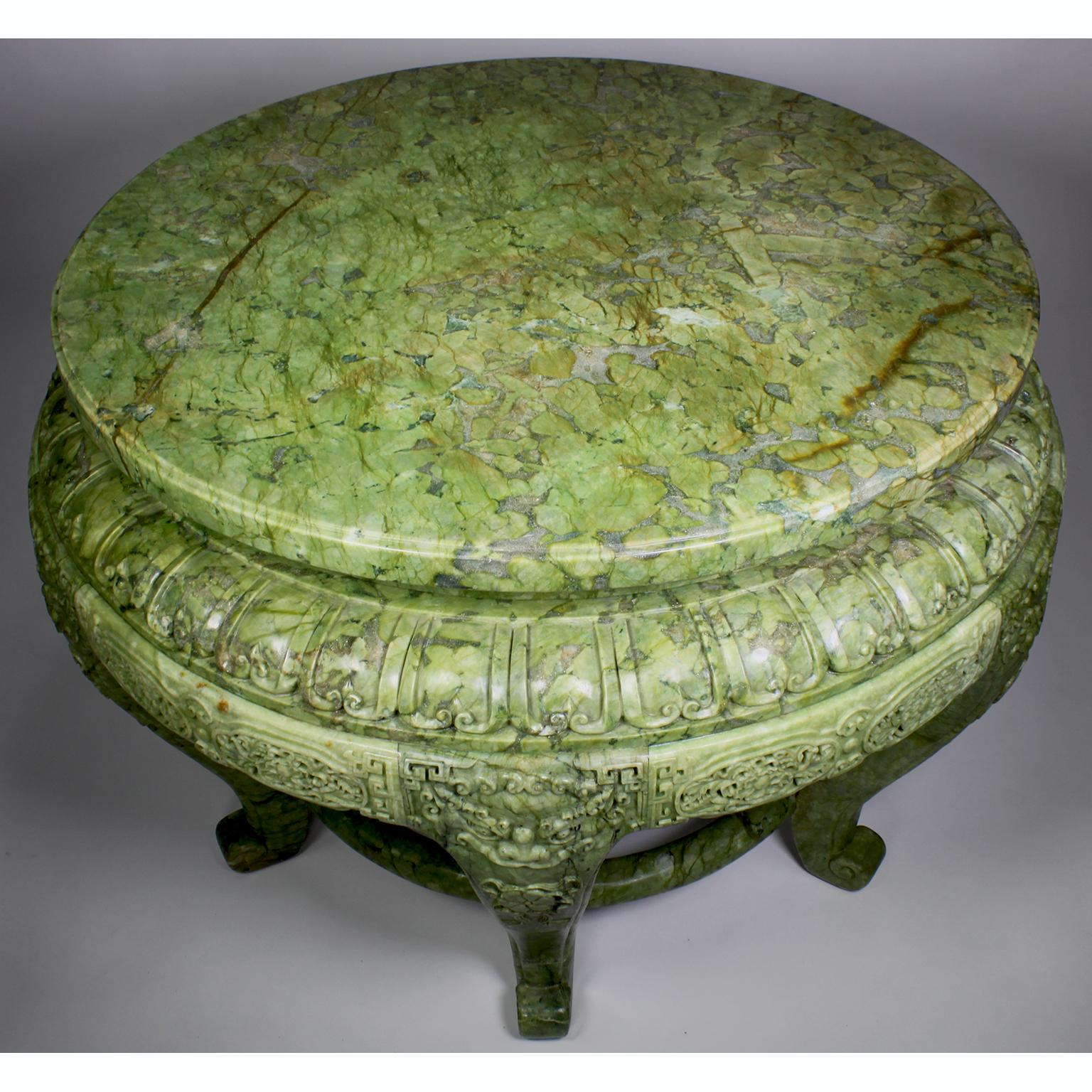 A Chinese late 20th century finely carved green serpentine center table. The six-legged pedestal table entirely carved of green serpentine, with a pierced apron in a Cantonese design, flanked on top of each leg with relief carvings depicting Foo