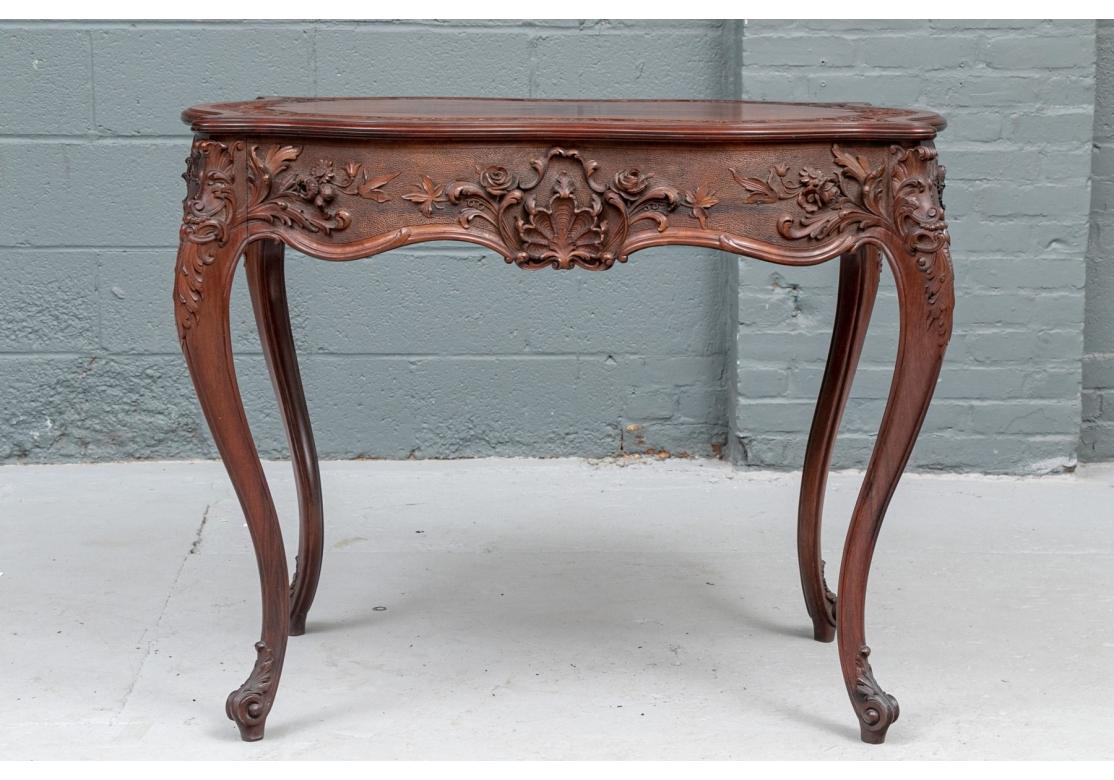A fine parlor table with a turtle top form, having a carved swirling leaf and scroll banding around the perimeter.
Heavily carved apron on textured ground with shells, floral arrangements and acanthus leaves. Stands on 4 cabriole legs with leaf