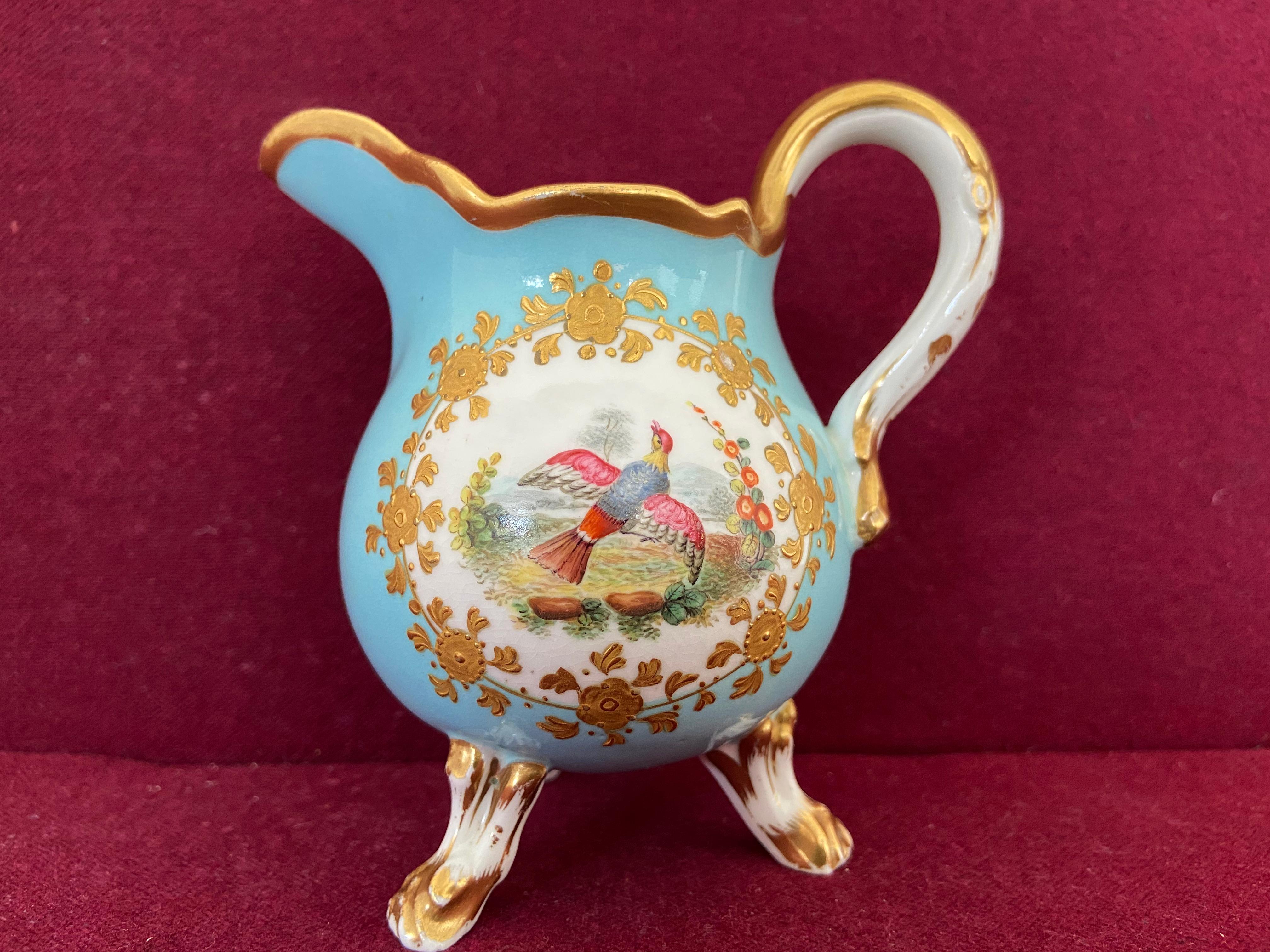 A fine Coalport Porcelain Creamer c.1835 standing on three legs. Decorated with a fancy bird in a roundel with raised gilt decoration on a duck egg blue ground.  The painted bird decoration is in the manner of John Randall. Unmarked.

Condition: