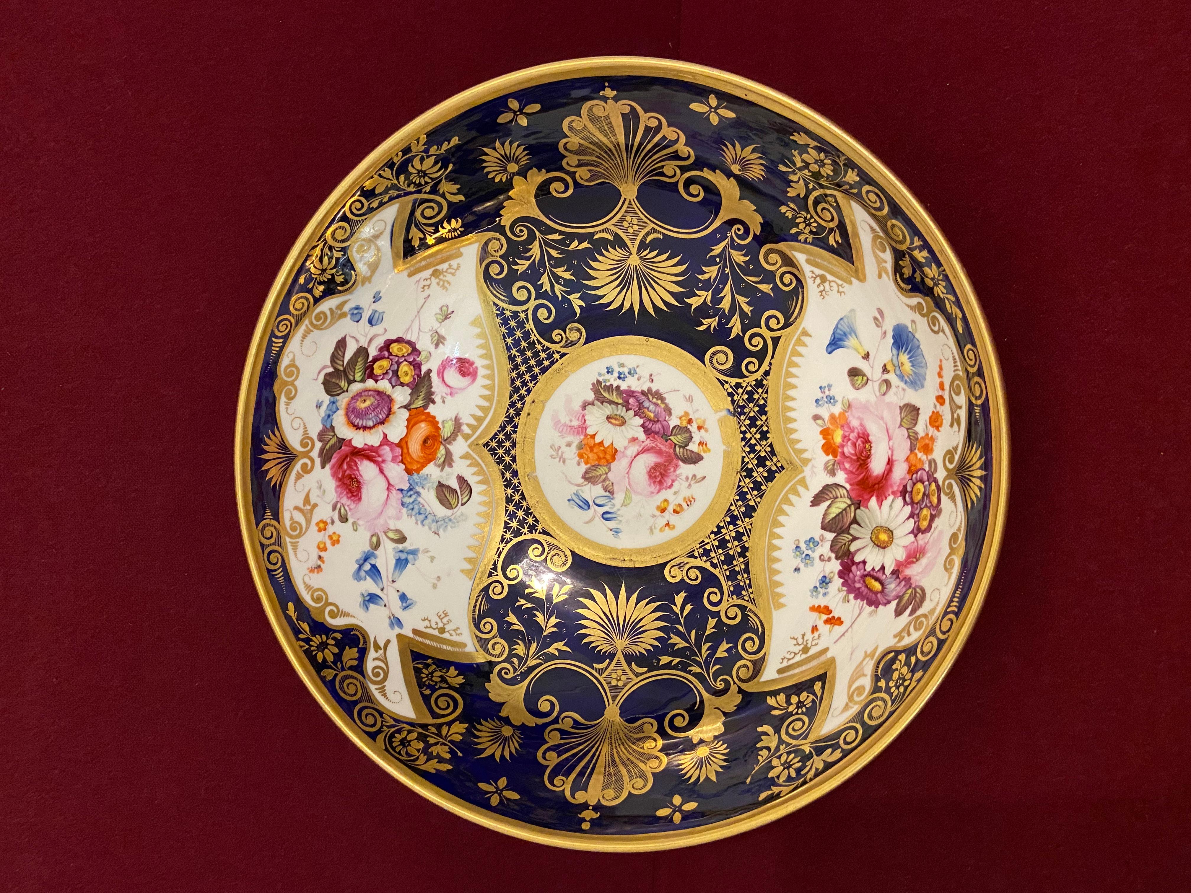 A fine Coalport porcelain punch bowl c.1820. Decorated with panels of flowers on a rich cobalt blue ground with richly embelished gilt decoration:

Condition: Two very small rim chips to the foot.