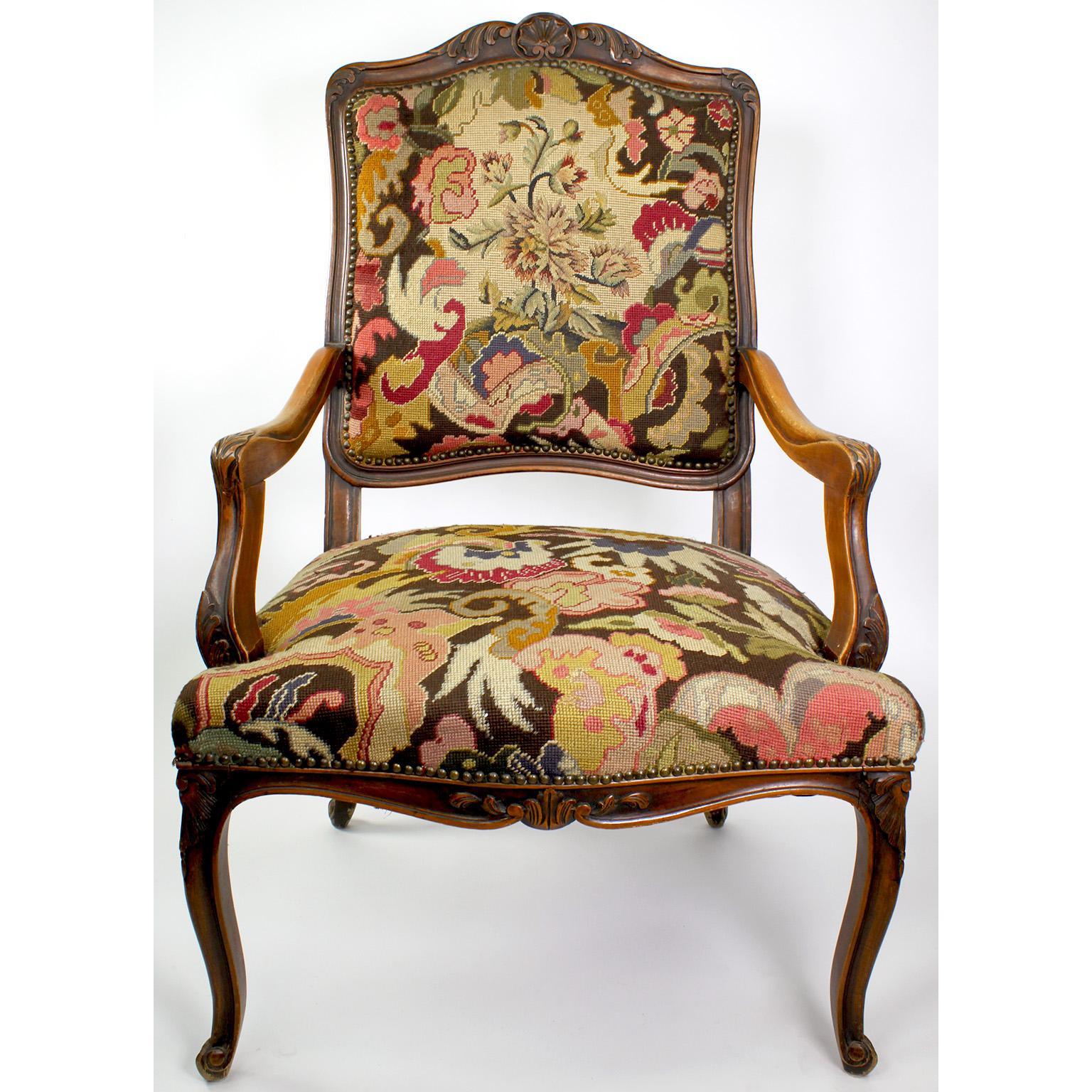 Fauteuil à la Reine en noyer sculpté, de style Louis XV, du 19e au 20e siècle. Le cadre en bois finement sculpté avec des accoudoirs ouverts et des pieds en cabriolet, est tapissé d'une tapisserie à l'aiguille. Circa : 1900.

Mesures : Hauteur :