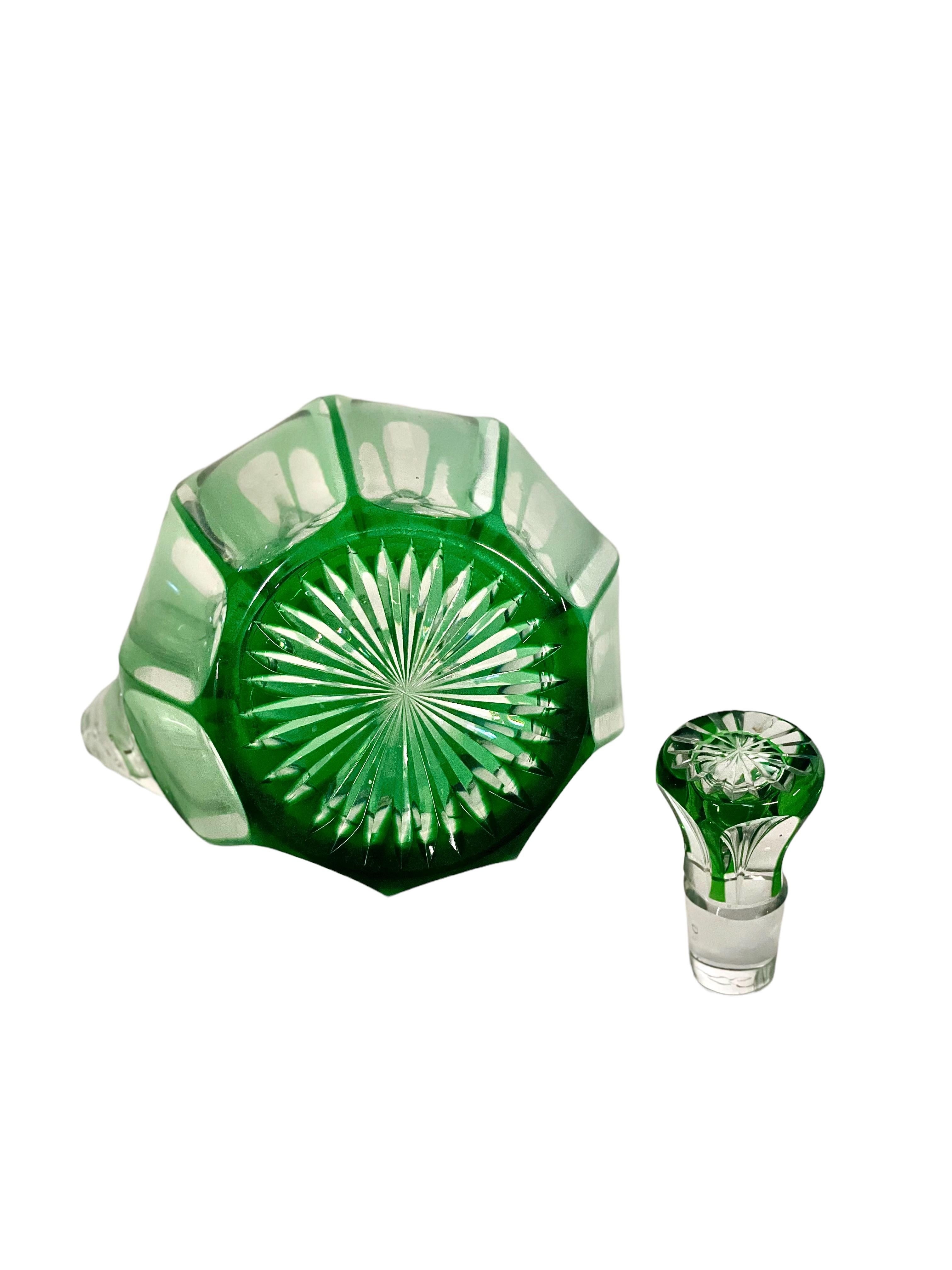 A fine liqueur decanter with handle and vibrant green cut-to-clear overlay. The star-cut base adds a decorative touch from below, while the sturdy stopper is cut and overlaid to match. This decanter is very heavy, and is of fine quality. It would