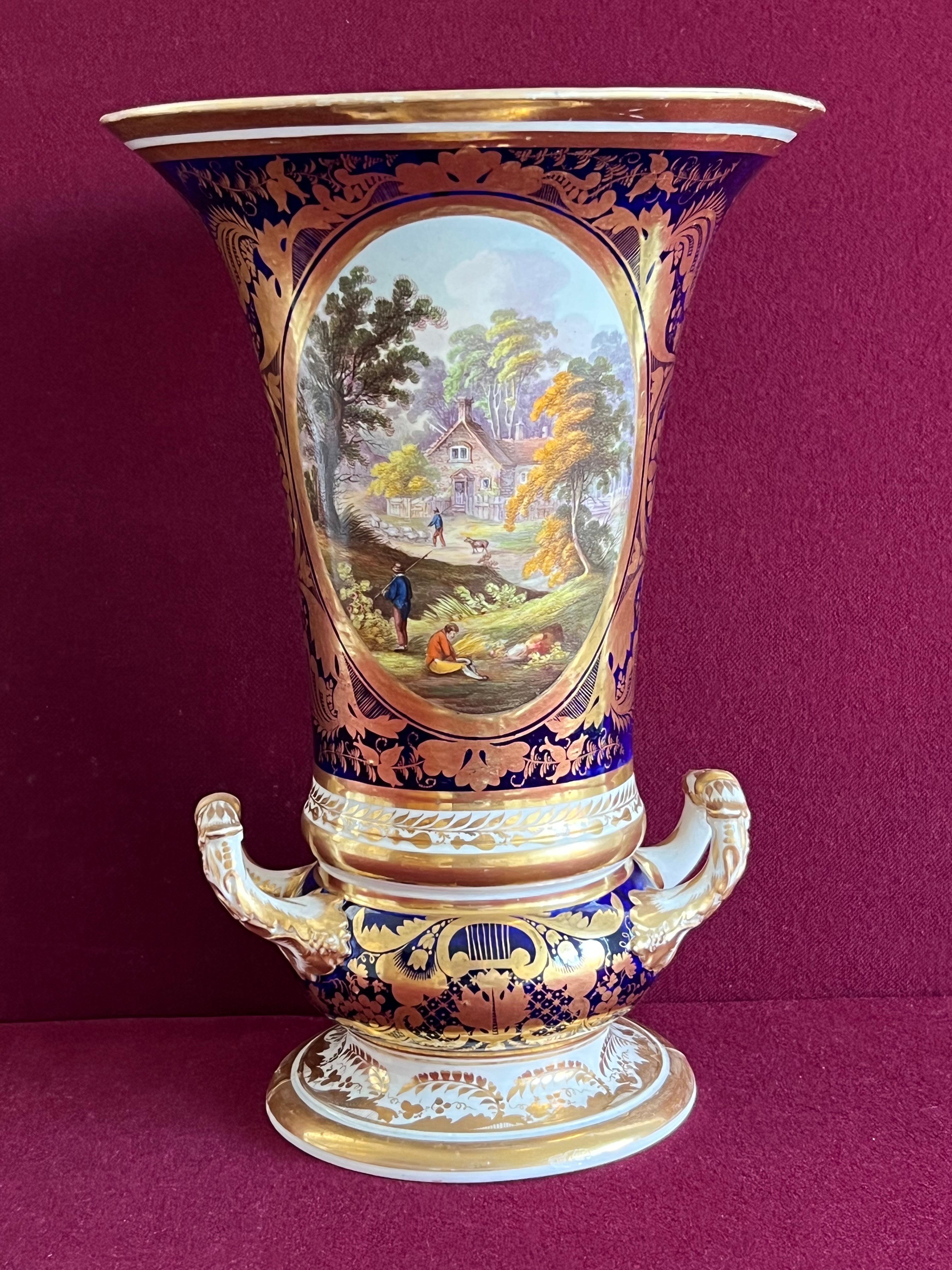 A fine Derby porcelain vase c.1810. Of elongated campana form with two gilded scrolled leaf mount handles and on a spreading circular foot with foliate gilt decoration and gilt band edge. The body is decorated with a large finely painted oval panel