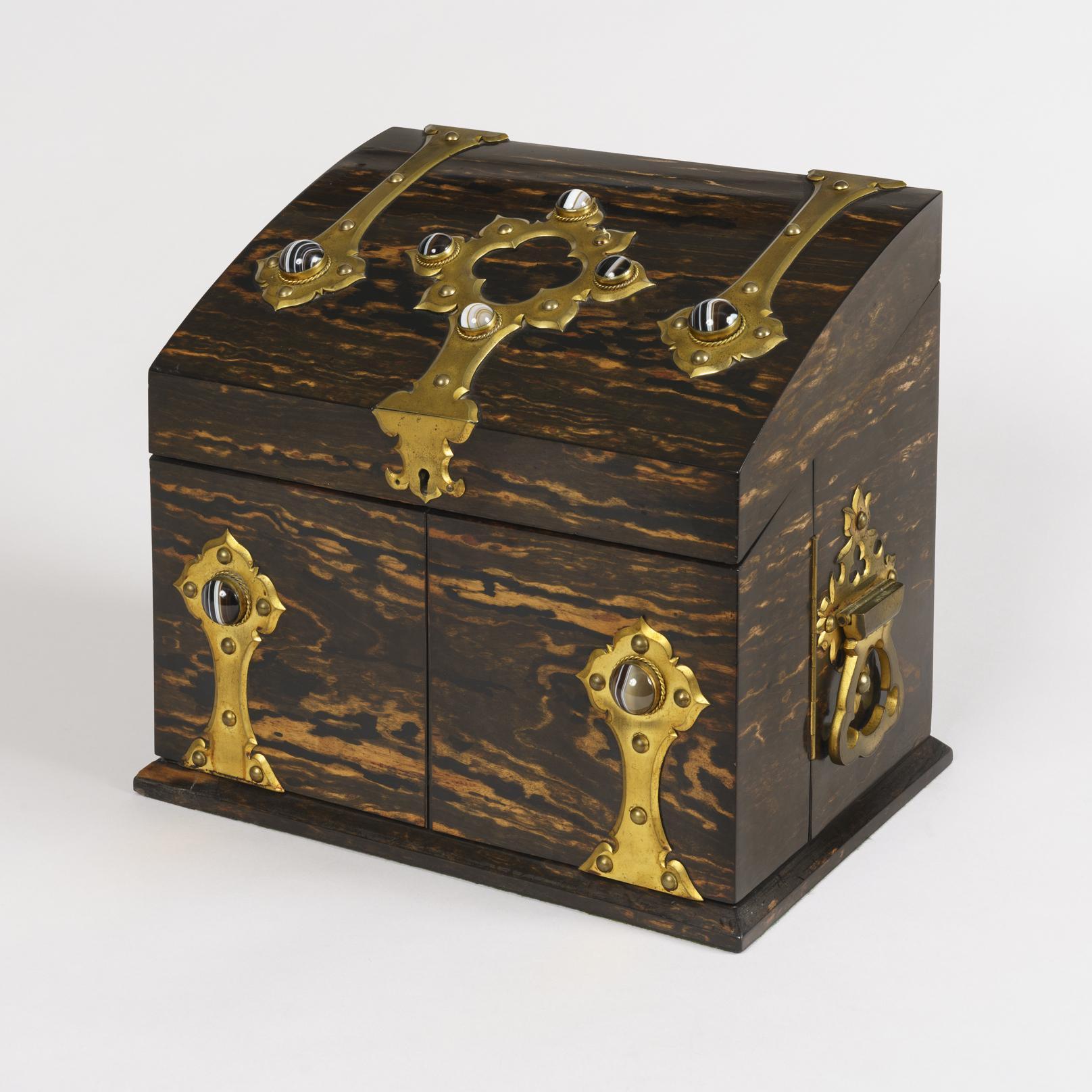 A Fine Drinks Box retailed by Spiers of Oxford.

Constructed in coromandel, dressed with gothic style bronze handles, and cabochon Tiger's Eye gemstones to the top; opening to reveal two hinged side wings each housing two wine glasses, with the