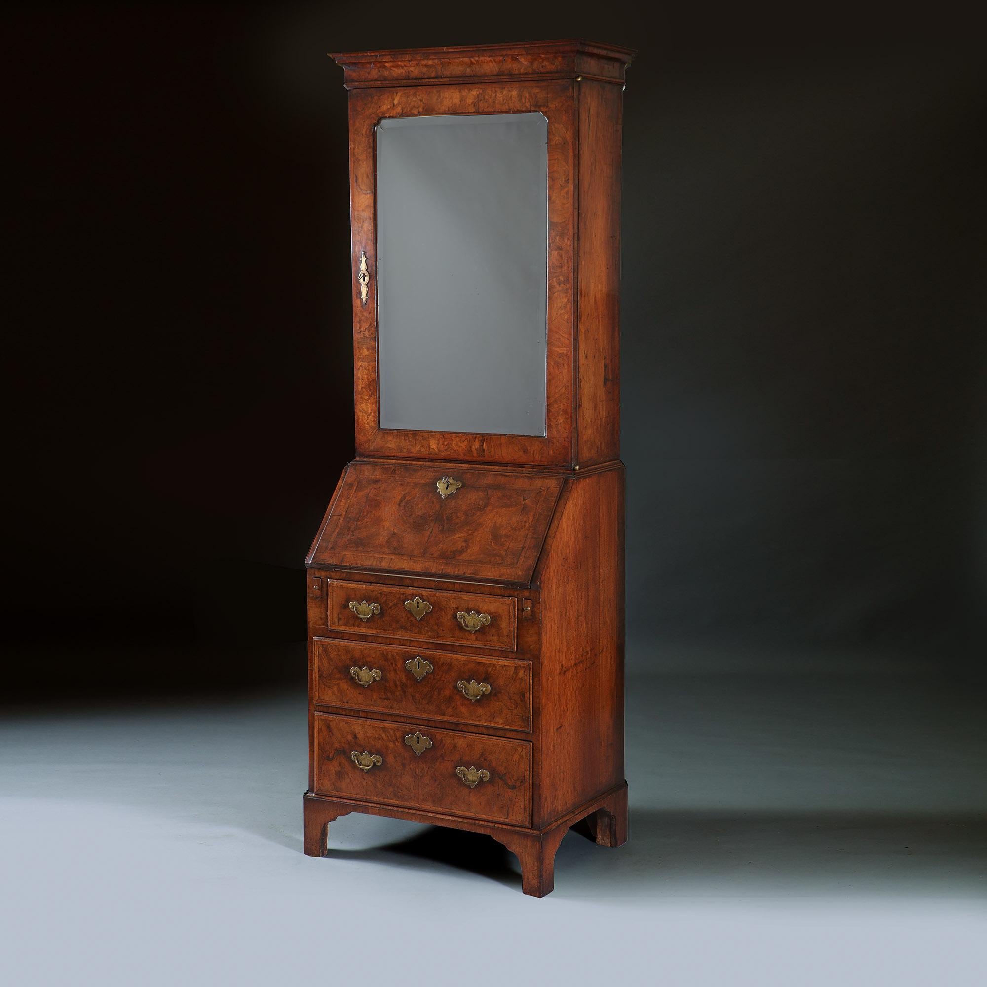 A fine early 18th-century George I burr walnut veneered bureau bookcase of diminutive proportions, circa 1715.

In two parts divided by a cross-grain moulding. The upper section has a cavetto cornice above a large single door inset with a shaped