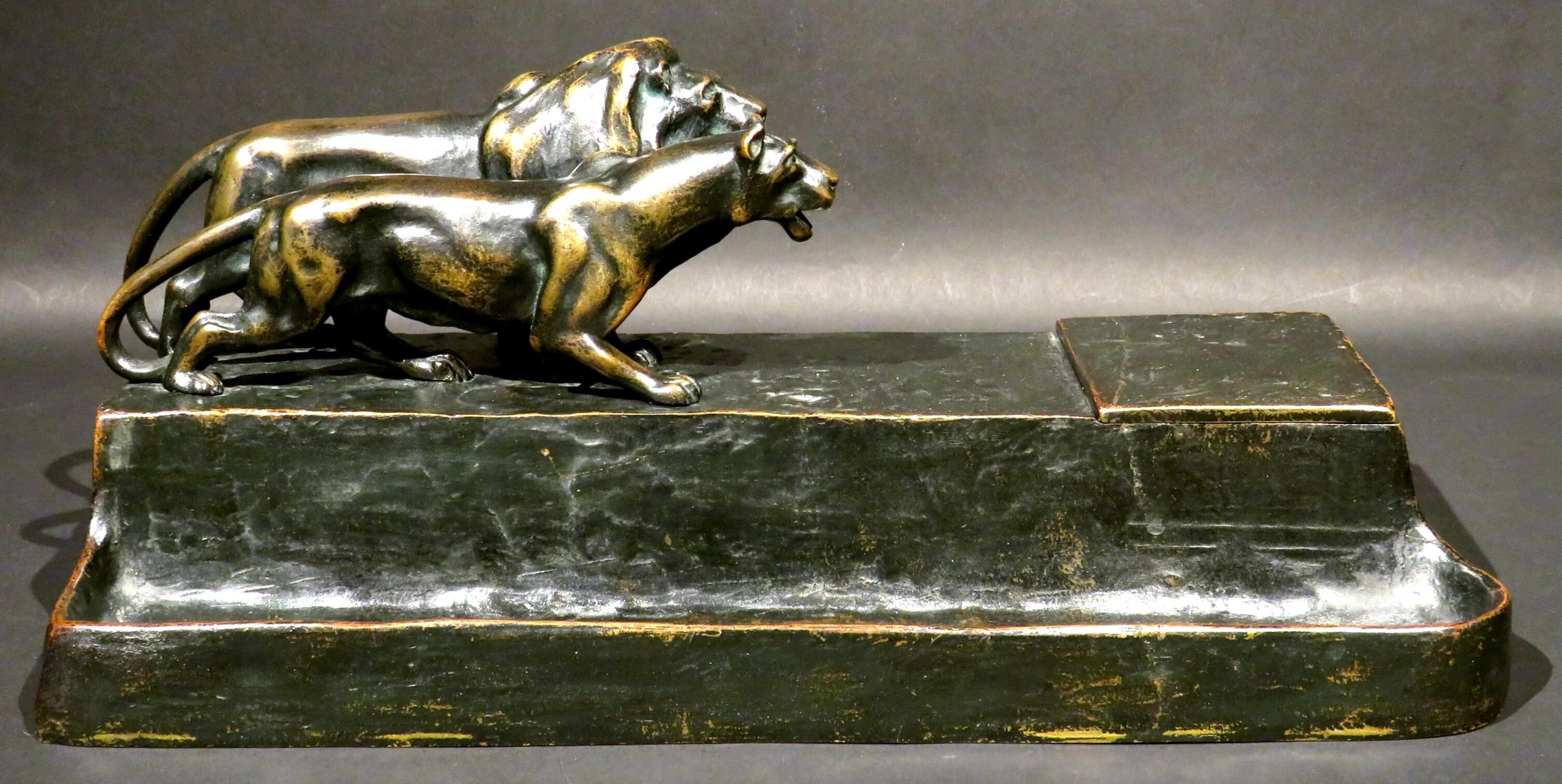 A very handsome early 20th century figural bronze inkstand depicting the finely modelled figures of a lion & lioness striding across a naturalistic ground, both figures demonstrating fine muscular detail & movement. 
Positioned far right is a hinged