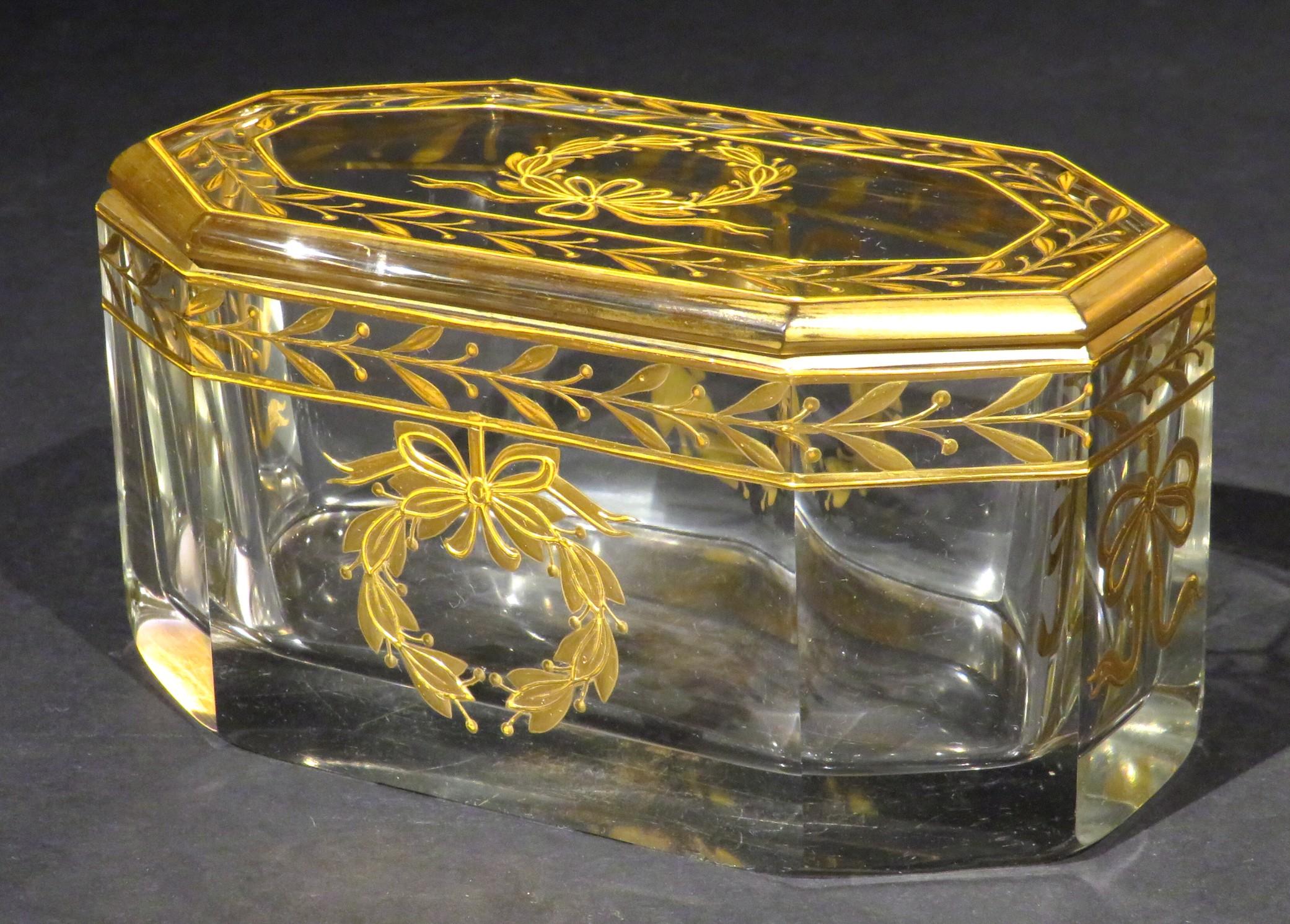A fine and very elegant early 20th century French glass dresser box, showing a rectangular shaped & eight sided base fitted with a conforming lid, both richly decorated with hand applied neoclassical gilt motifs.