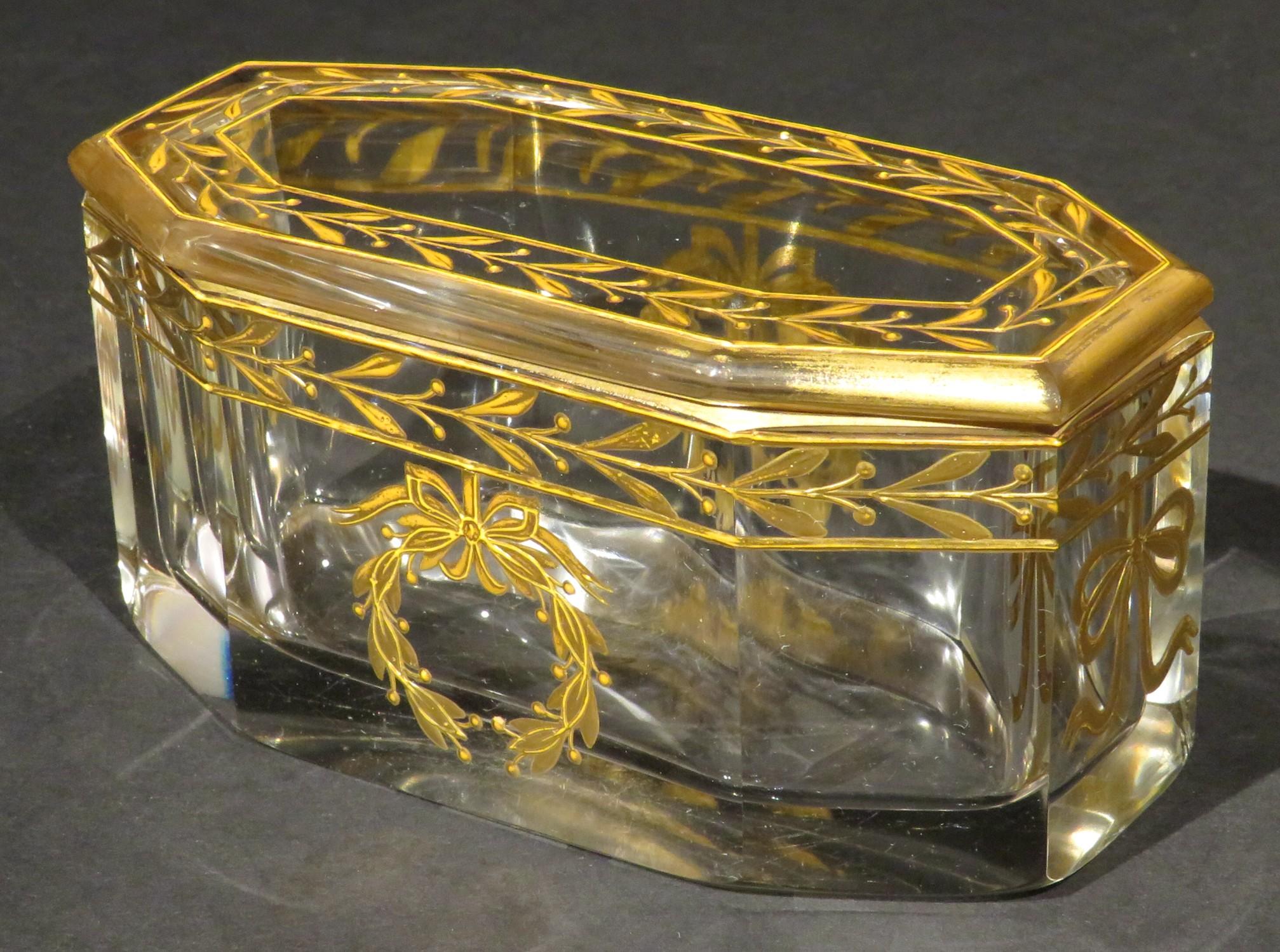 A very elegant early 20th century French glass dresser box or jar, showing a rectangular shaped & eight sided base fitted with a conforming lid, both richly decorated with hand applied neoclassical gilt motifs.