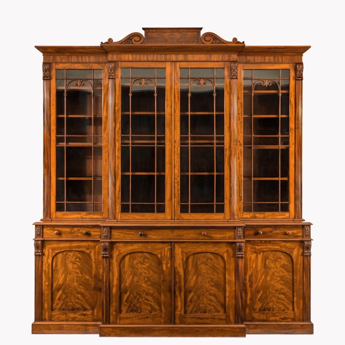 A fine early William IV mahogany breakfront bookcase firmly attributed Gillows of Lancaster, in four sections, the top with astragal glazed doors enclosing four adjustable shelves between reeded pilasters with anthemion scroll corbels, the base with