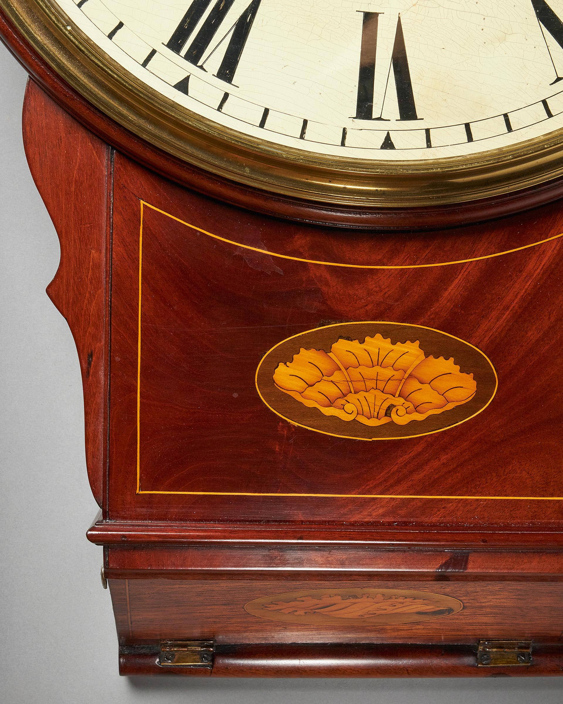 A lovely and attractive English trunk dial clock made c. 1840. 

The mahogany veneered case is of an original design with slightly shaped sides to the trunk and a Sheraton-like shell inlay in the middle accentuated by a satinwood line inlay. It