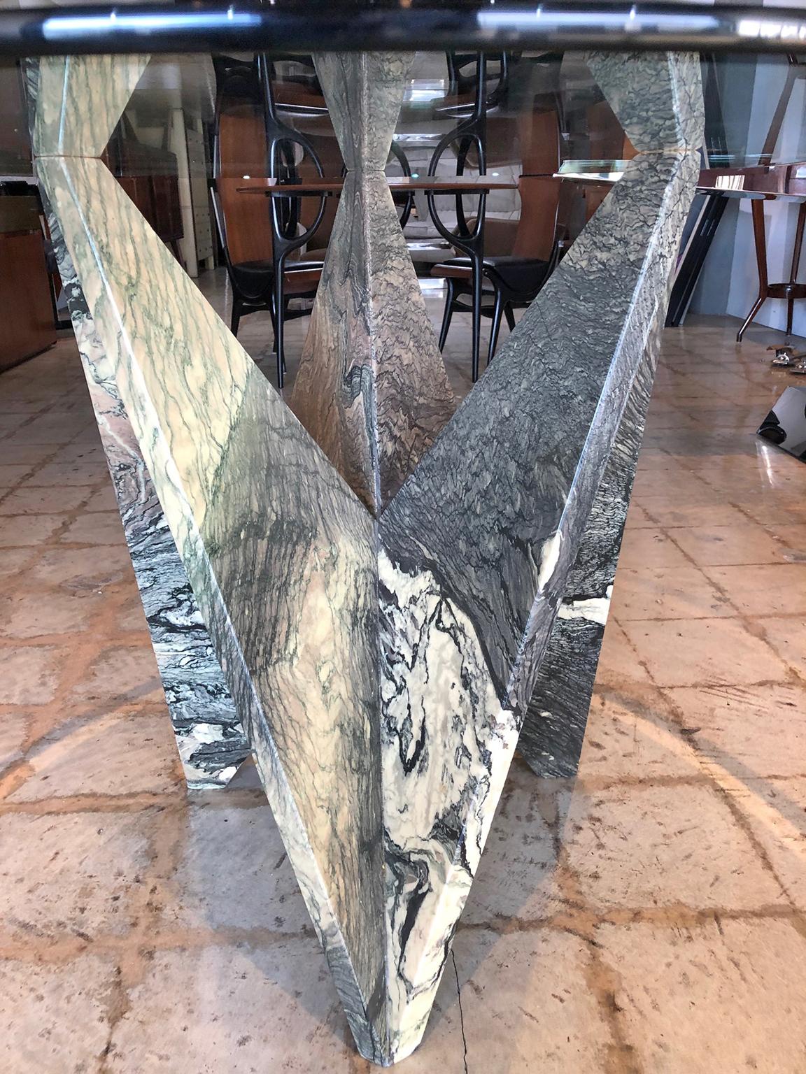 A faceted table of serpentine marble with veining of dark greens and blacks on a cream field. 
Designed by Ferrari.