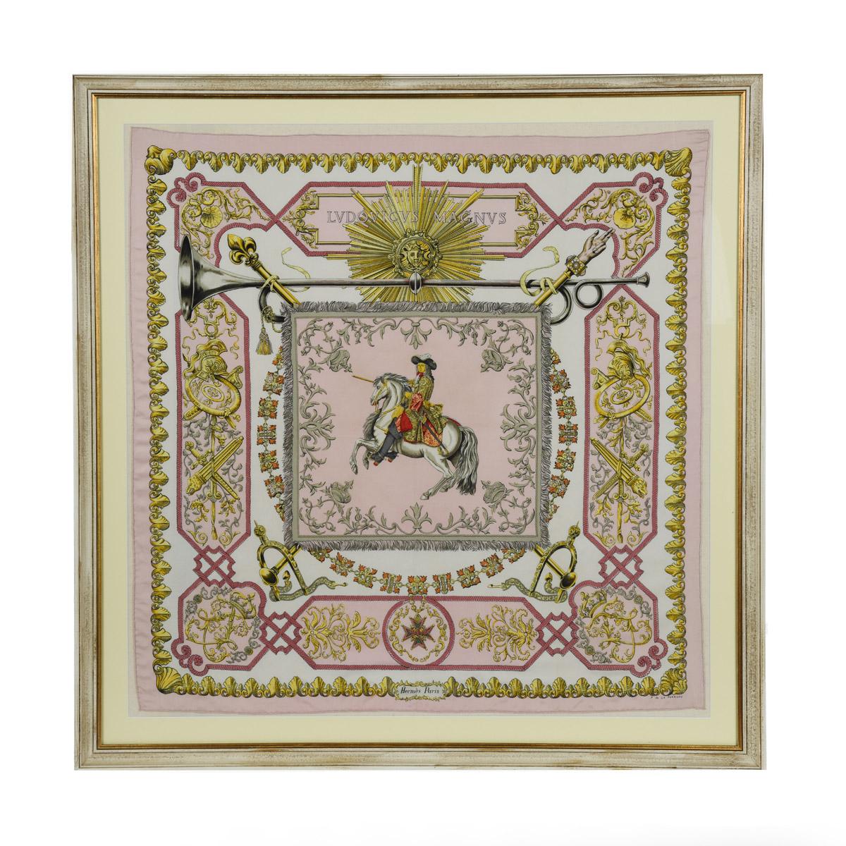 A fine framed Hermès 90 silk square of Ludvicus Magnus (Louis XIV) designed by Françoise de la Perriere, circa 1963, predominantly in pink and gold, showing the Sun King in full court dress on a rearing grey stallion, the borders comprising the
