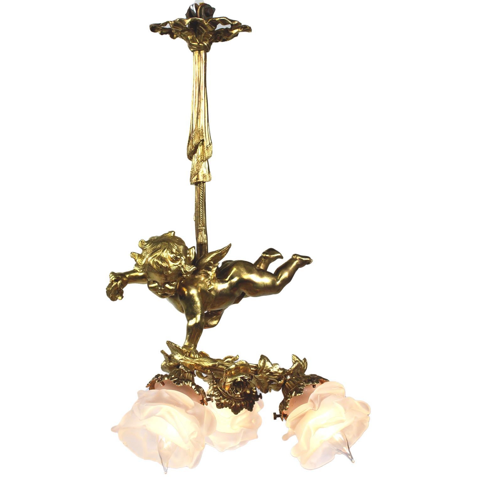 A fine and charming whimsical French 19th/20th century belle époque three light gilt bronze figural chandelier pendant. The charming gilt bronze figure of a naked hovering winged cherub or cupid, suspended from a ribbon-tied tassel wrapped around