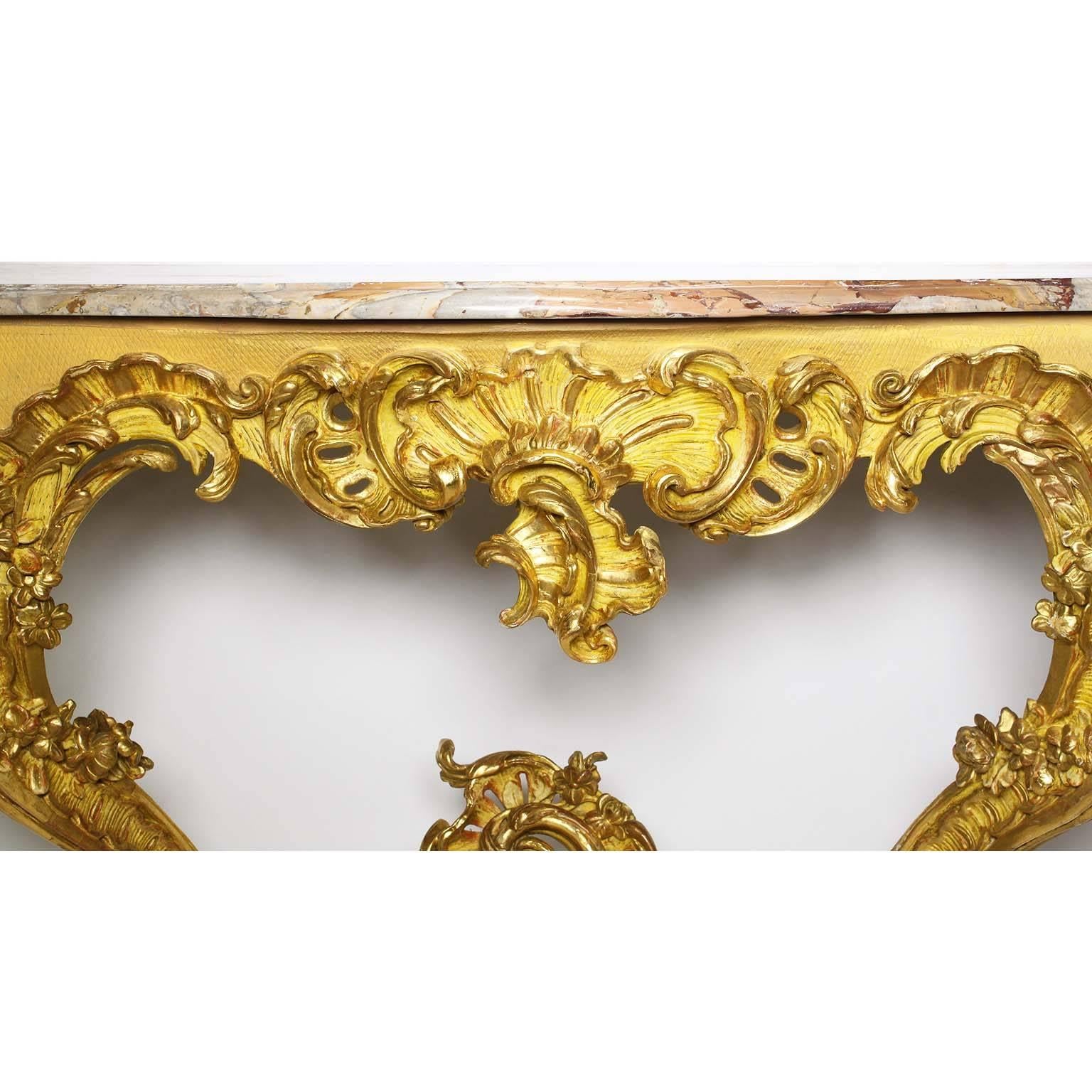 A very fine French 19th century Louis XV style Rococo giltwood carved console table with marble top. The ornately carved serpentine frame with a shell and scrolled apron with a gilt and yellow primer background, raised on dual front 