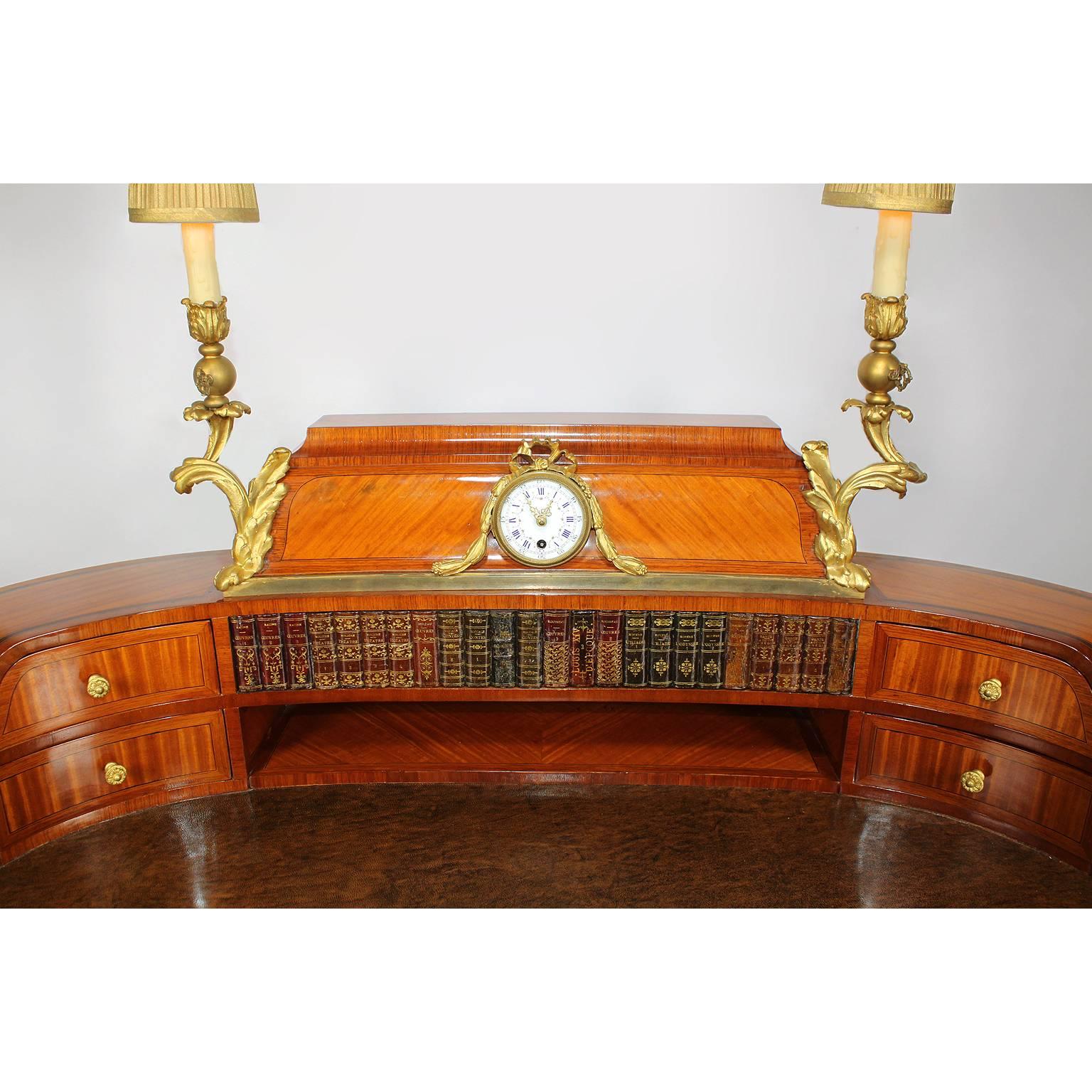 Raffinato scrittoio francese del XIX secolo in legno di tulipano, mogano e ormolatura, attribuito alla Maison Millet. La sovrastruttura è centrata da un orologio con il quadrante in porcellana decorato con fili di fiori e numeri romani sopra numeri