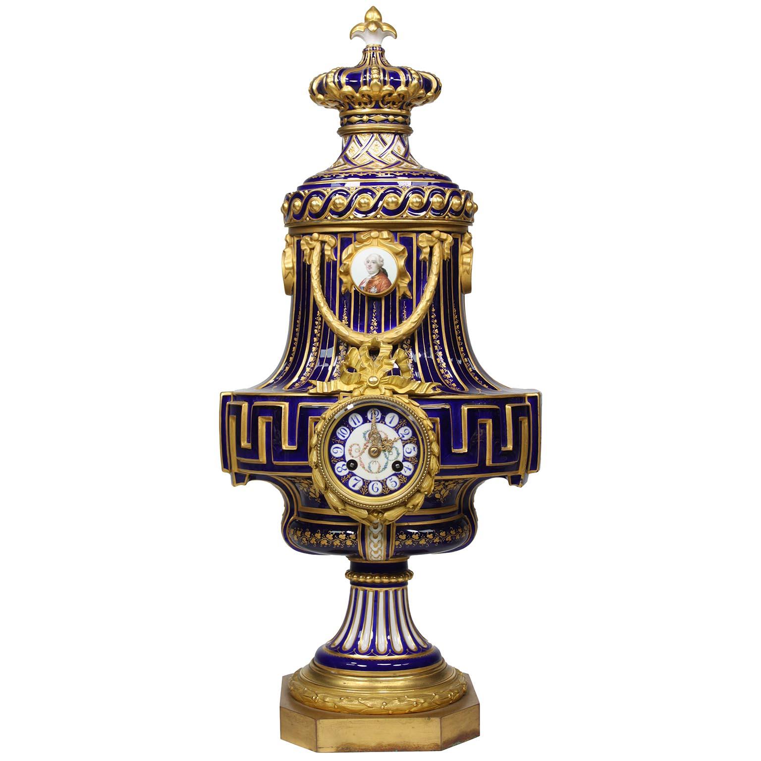 Raffinatissimo set di tre pezzi in porcellana di Sèvres del XIX secolo con fondo dorato e blu cobalto, ornato di ornamenti e orologi. Le urne da esposizione figurative finemente decorate, modellate su un modello di Jean-Claude Chambellan Duplessis,