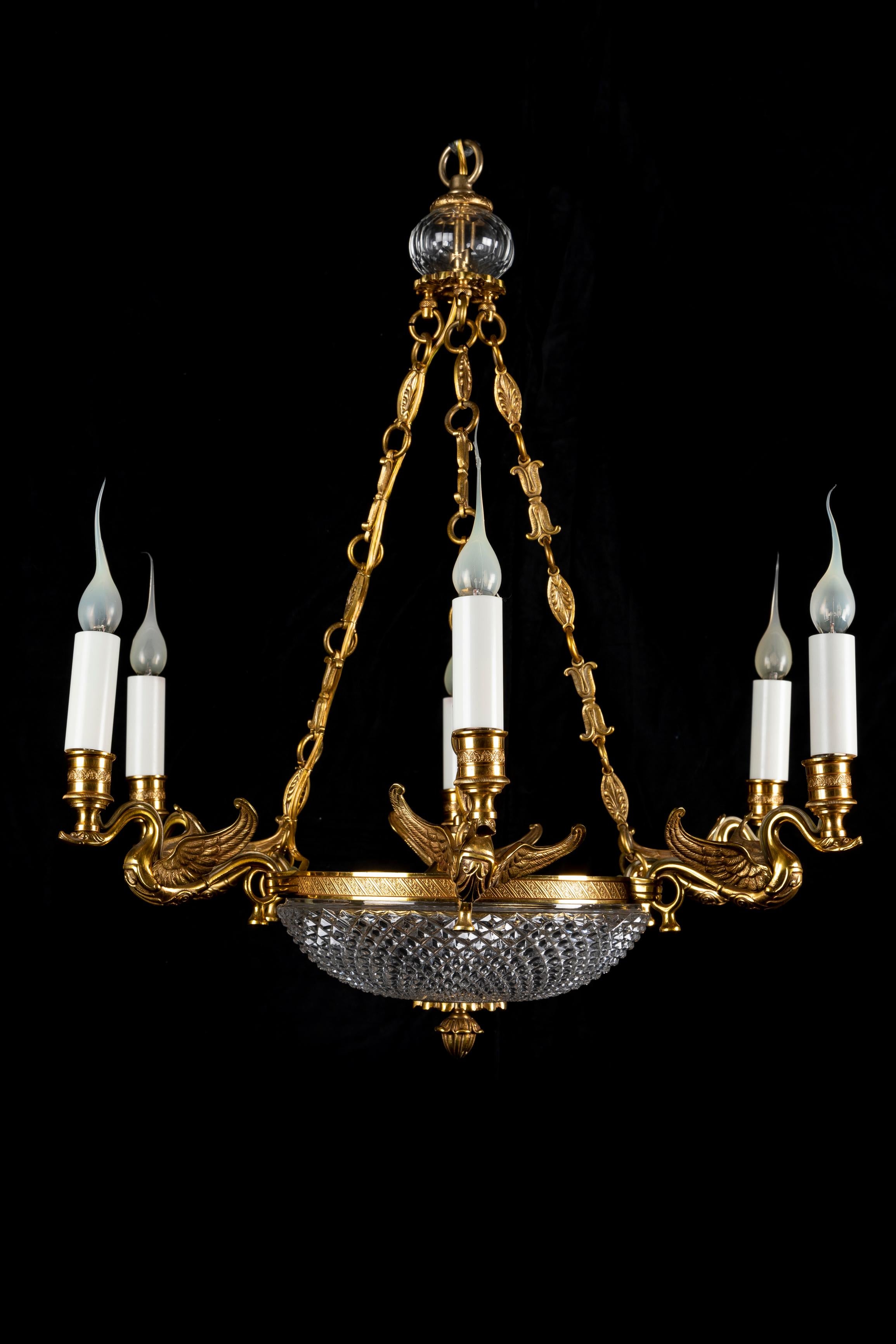 A FIne French Empire Style gilt bronze and cut crystal multi light swan chandelier. This exquisite chandelier is embellished with six beautiful gilt bronze swans, a round cut crystal dish and further adorned with gilt bronze chains connected to the