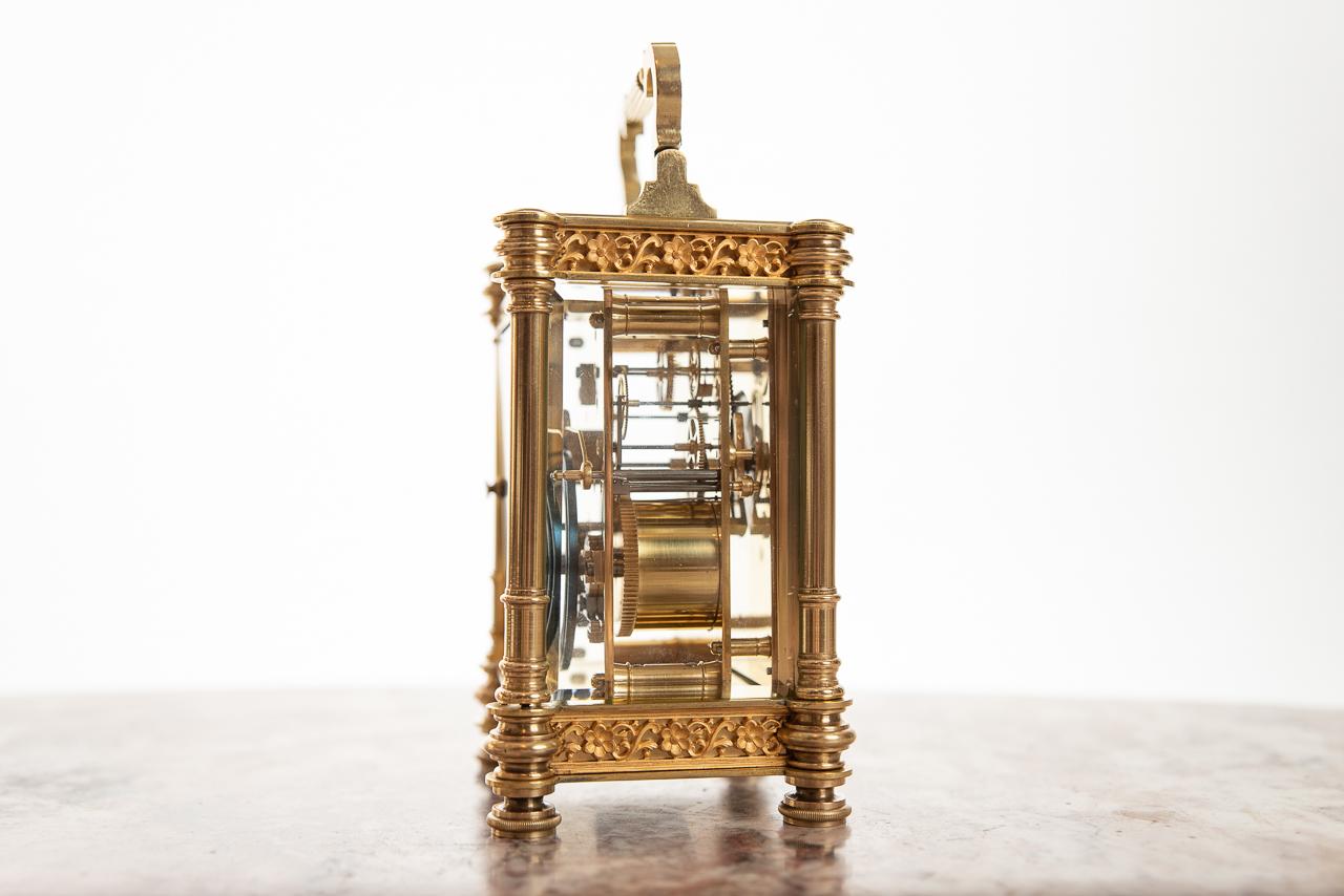 A fine French 8 day hour and half hour striking clock on a coiled gong. The brass cased carriage clock with architectural columns and gilt blind fret panels, cast with birds of paradise, flowers, and foliate scrolls. The dial has Arabic numerals. A
