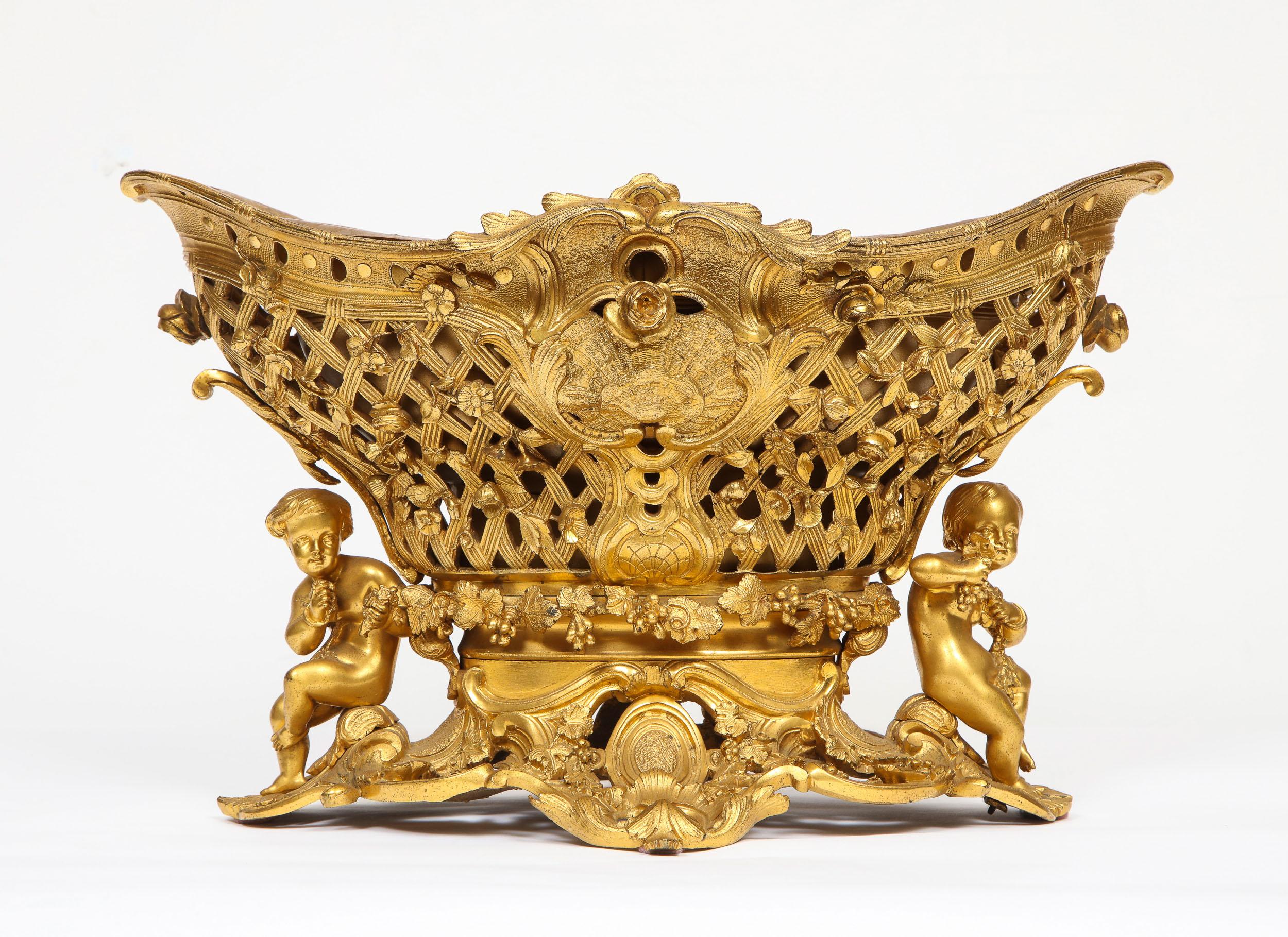 A fine French Rococo ormolu bronze basket centerpiece with Putti, Henri Picard, Paris, circa 1860.

Of navette form, reticulated basketweave, foliate handles, floral swags, and 2 seated putti. (removable lead liner)

Very fine quality and