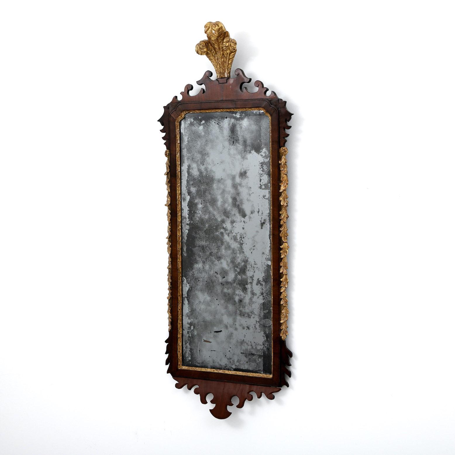 We presents a fine George I walnut and parcel gilt mirror.

England, Circa 1720.

” An elegant George I pier mirror with gilded ‘Prince-of-Wales’ feather crest, above a shaped rectangular bevelled plate within an incised gilt border and mahogany