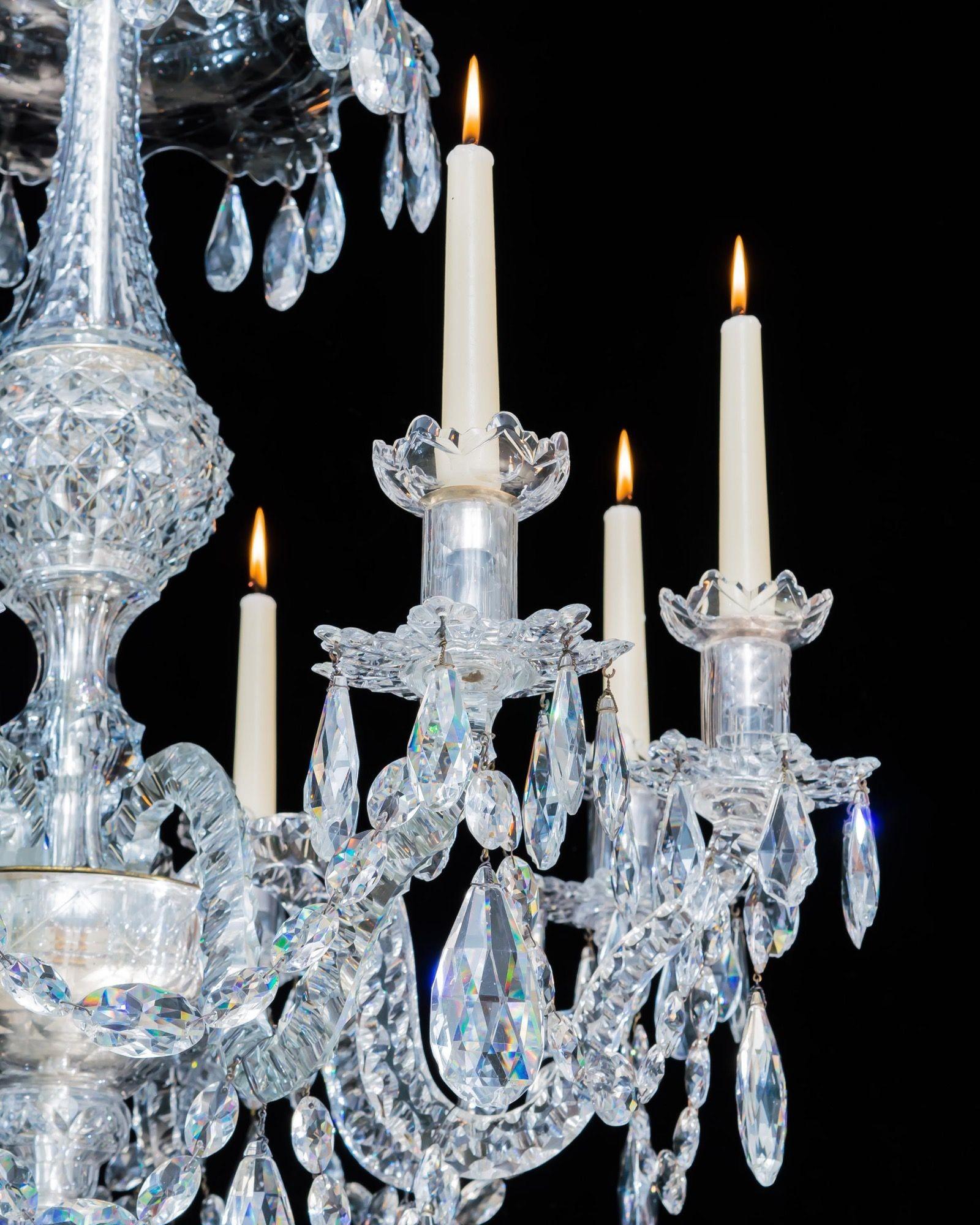 An exceptional quality chandelier of unusual form, the stem centralised with a heavy diamond cut sphere tapering to double drop hung canopies, the receiver bowl issuing eight notch cut double kick candle arms, supporting scalloped edge drip pans and