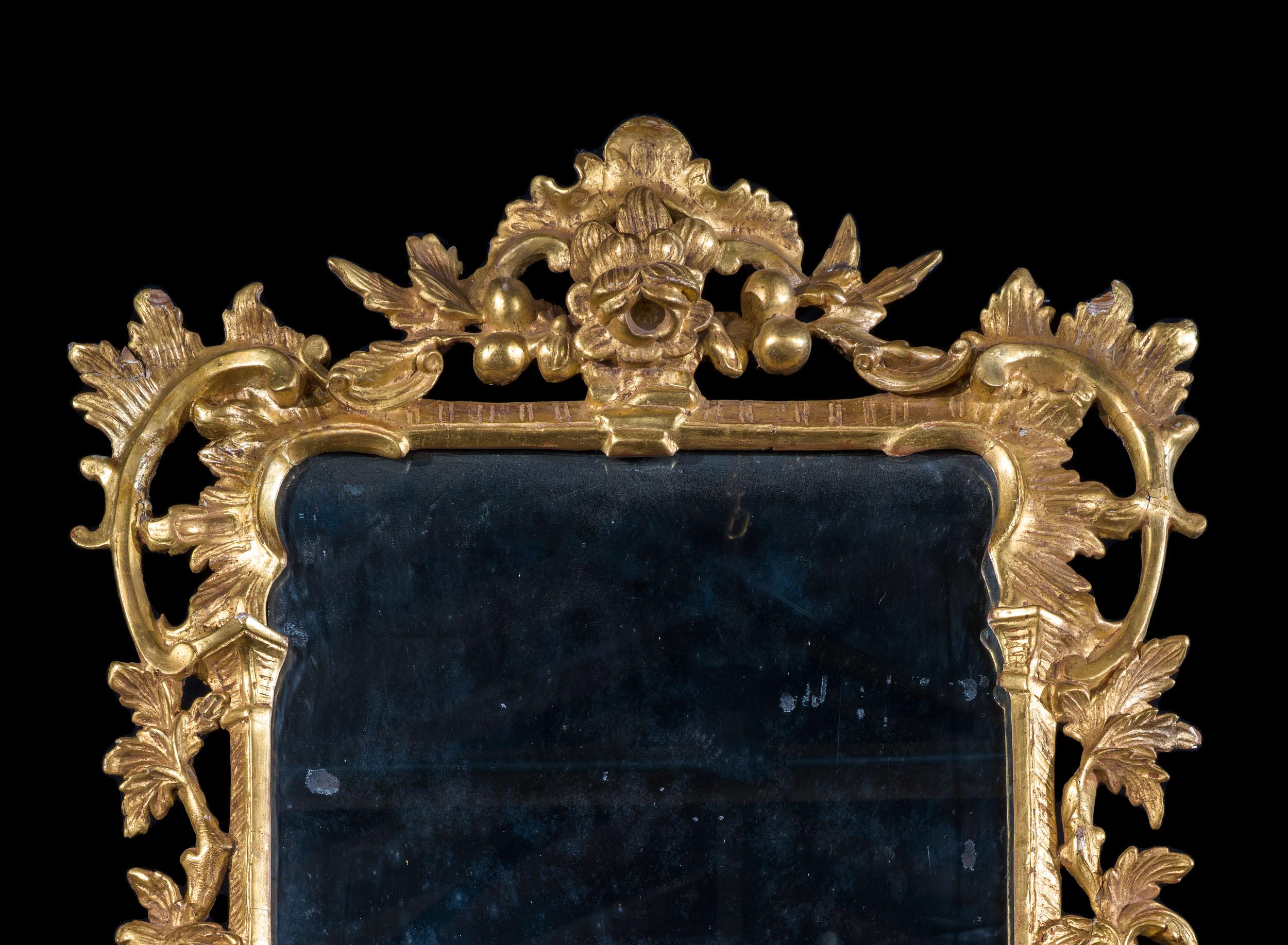 Un beau miroir mural en bois doré de George III, très proche de la manière de Chippendale, dont le cadre fin présente une profusion de rinceaux et de décorations foliaires stylisées entrelacées de manière naturaliste. Plaque de mercure