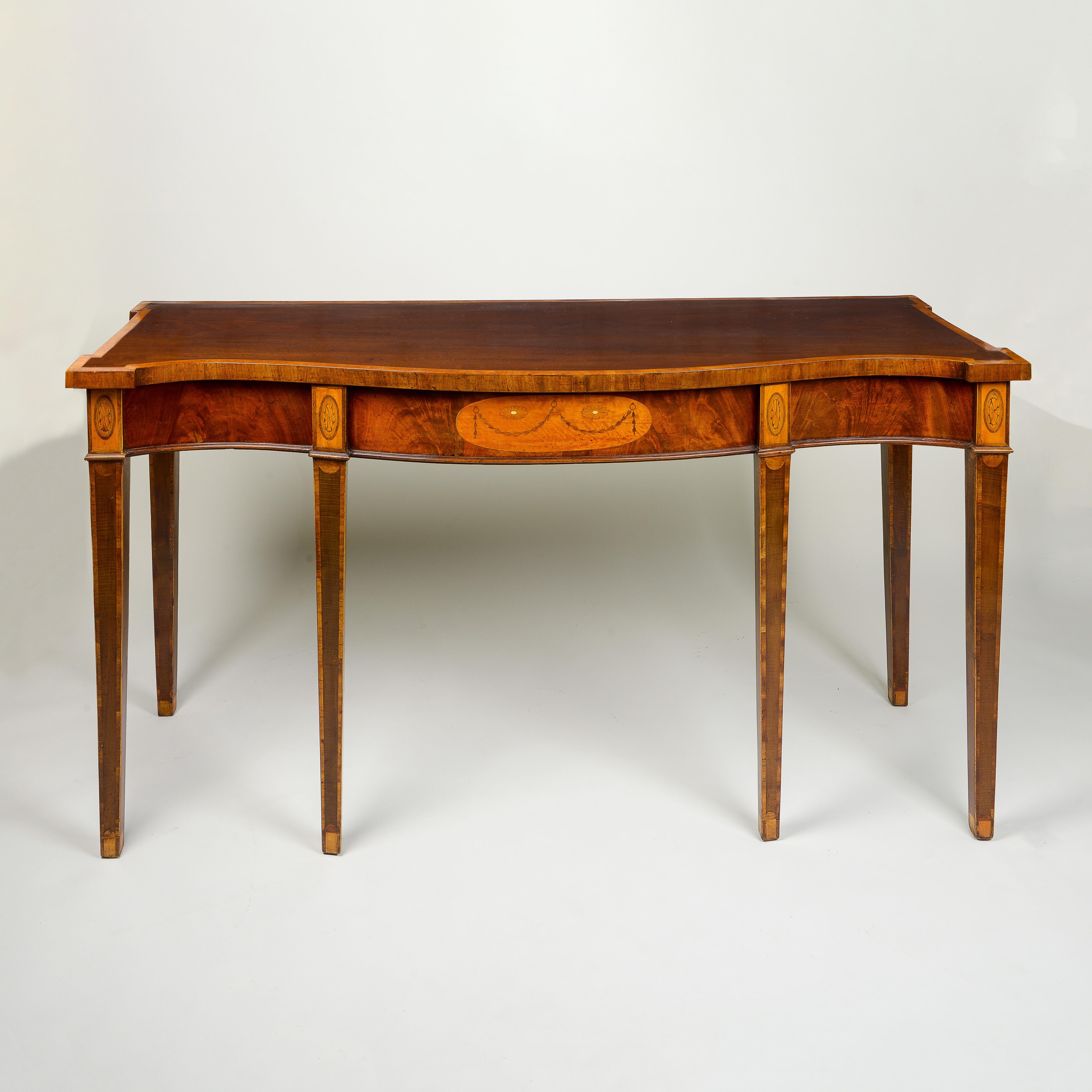 The rectangular serpentine-fronted top with outset corners and broad satinwood banding over a finely-figured frieze centered by an oval medallion inlaid with a bellflower garland on a satinwood ground; raised on four square satinwood-banded tapering