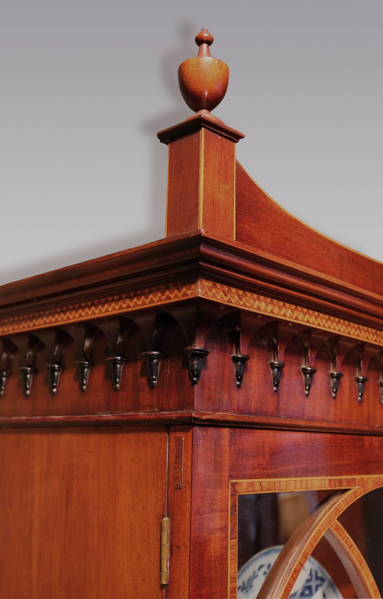 Pregevole libreria Secretaire in mogano ben figurato della fine del XVIII secolo, con cornice modanata con intarsi a scacchiera, sormontata da urne e pannello centrale intarsiato in legno di raso, sopra porte vetrate astragali sagomate a fasce