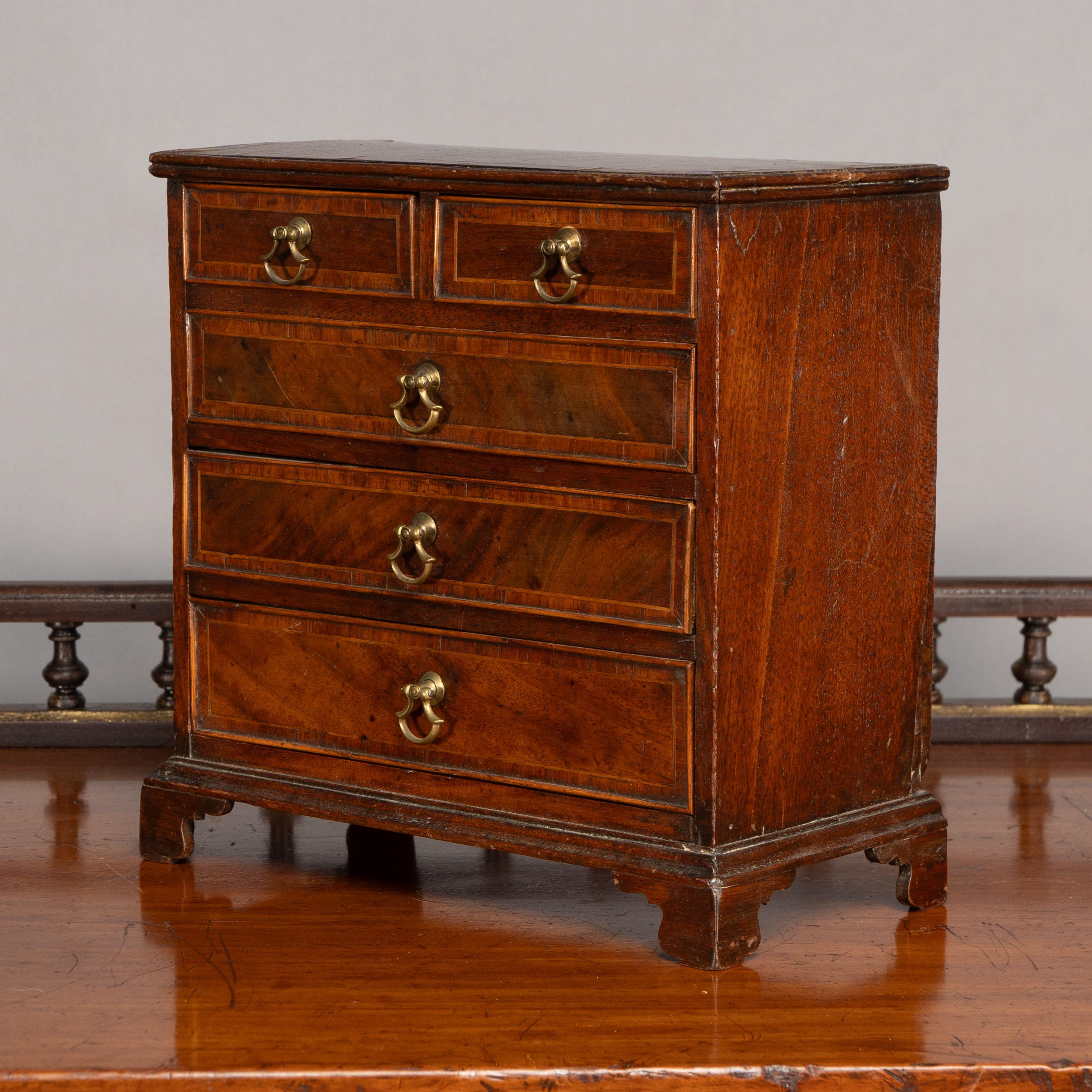 Una bella cassettiera in miniatura in noce georgiano con fascia in legno di tulipano e maniglie in ottone d'epoca fatte a mano, su piedi a staffa.