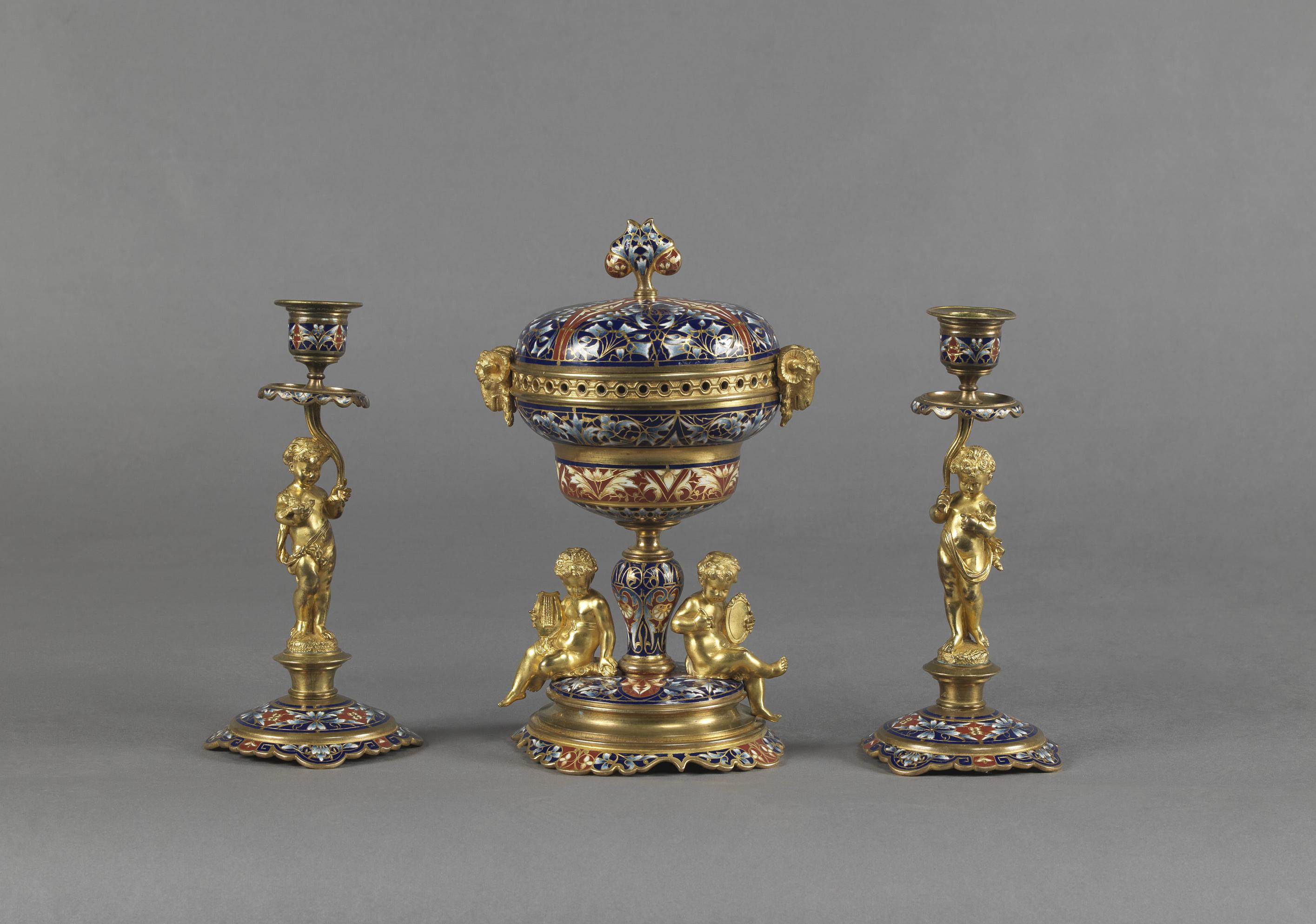 A fine gilt bronze and Champlevé Enamel Garniture Set comprising a pair of candelabra and a brûle-parfum and cover. 

French, circa 1890.

The brûle -parfum or censor with a domed champlevé enamel lid above a gilt bronze pierced guilloche border