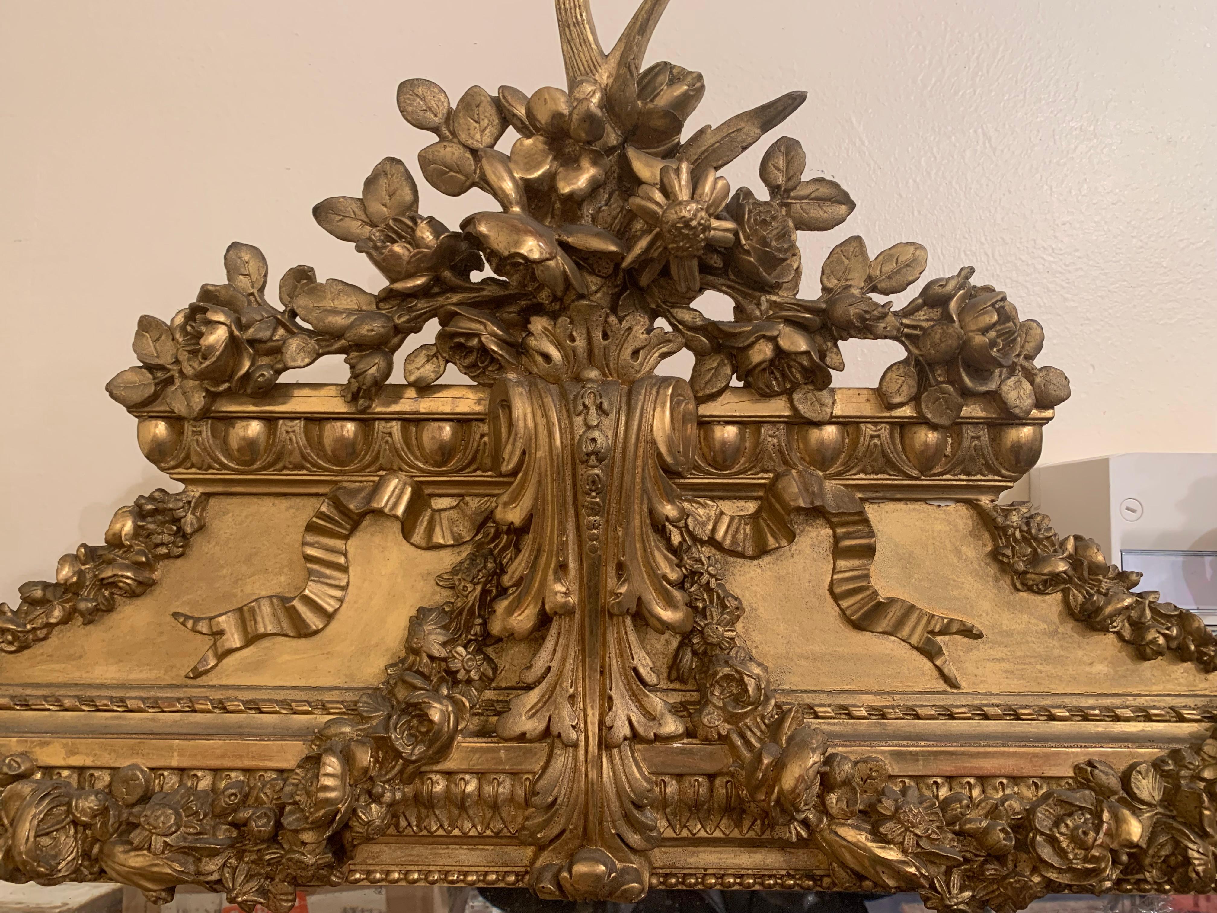 Un elegantissimo specchio in legno dorato francese del XIX secolo Luigi XVI. Lo specchio conserva la piastra originale. Un'incantevole cornice riccamente intagliata con grandi foglie a voluta in ogni angolo, mentre al centro si trova