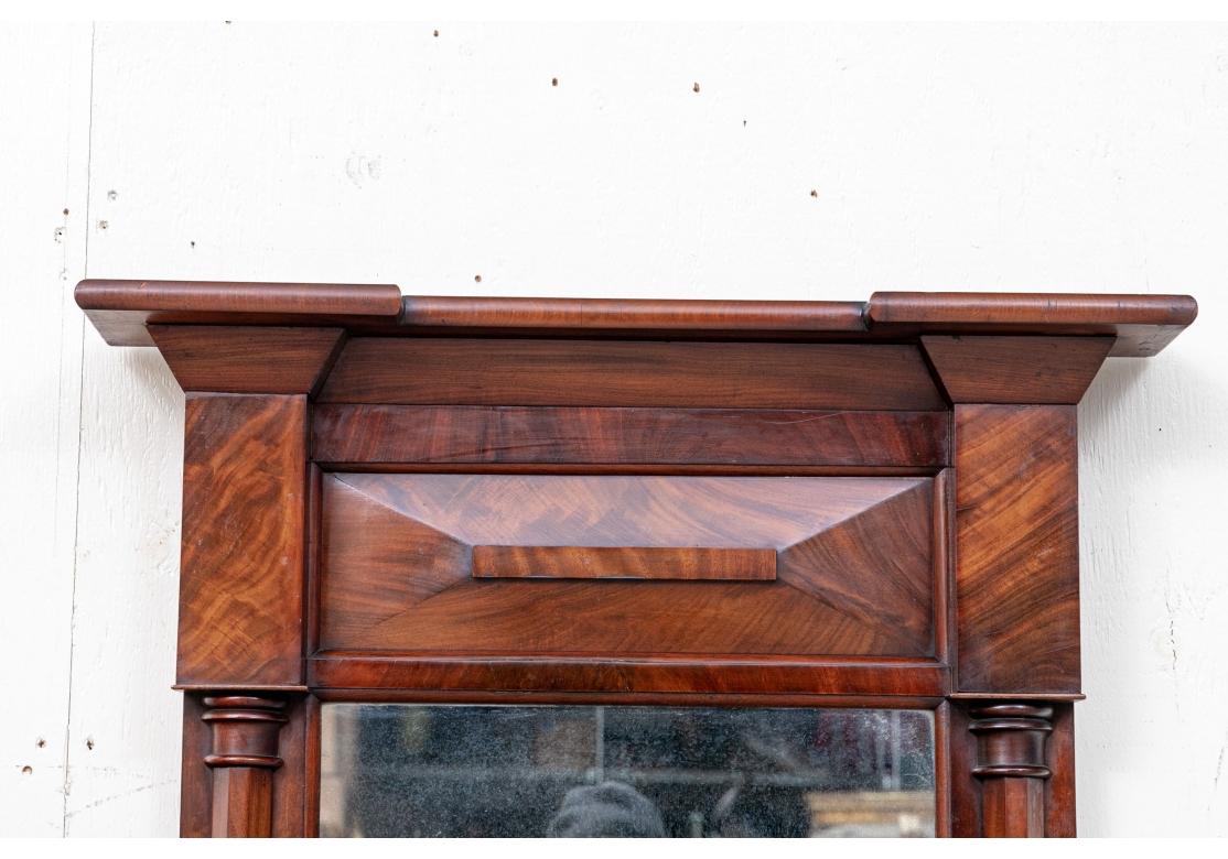 A more diminutive Federal style Pier Mirror with traditional form and particularly rich color and graining. Highly figured mahogany pier mirror with a dimensional crest and two faceted columns flanking the mirror glass. The back with wood and a