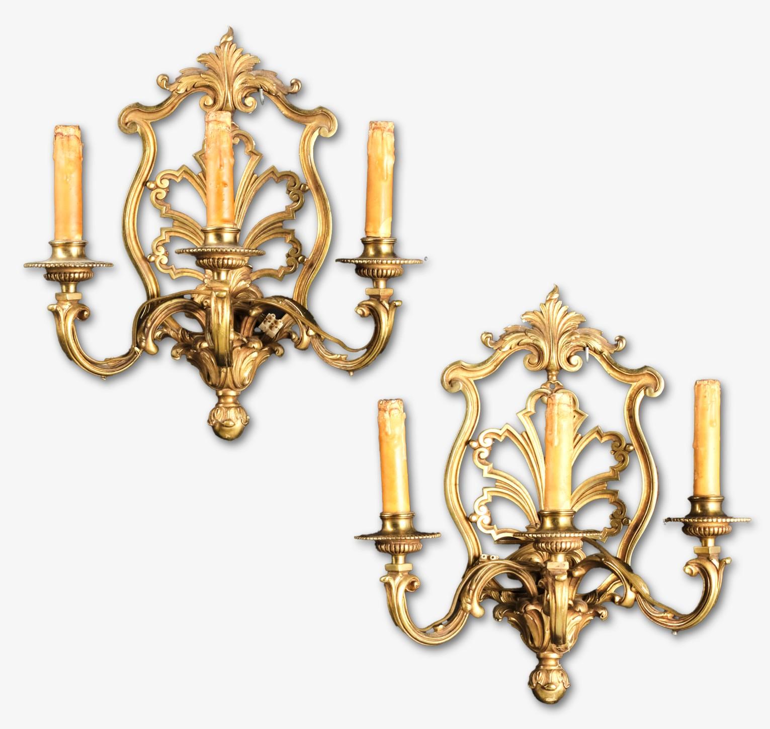 Coppia di appliques in bronzo dorato in stile rococò, molto belle e riccamente fuse, che presentano piastre posteriori a forma di cartiglio e rocaille traforate con elementi foliati finemente cesellati, che sorreggono un trio di rami fusi foliati