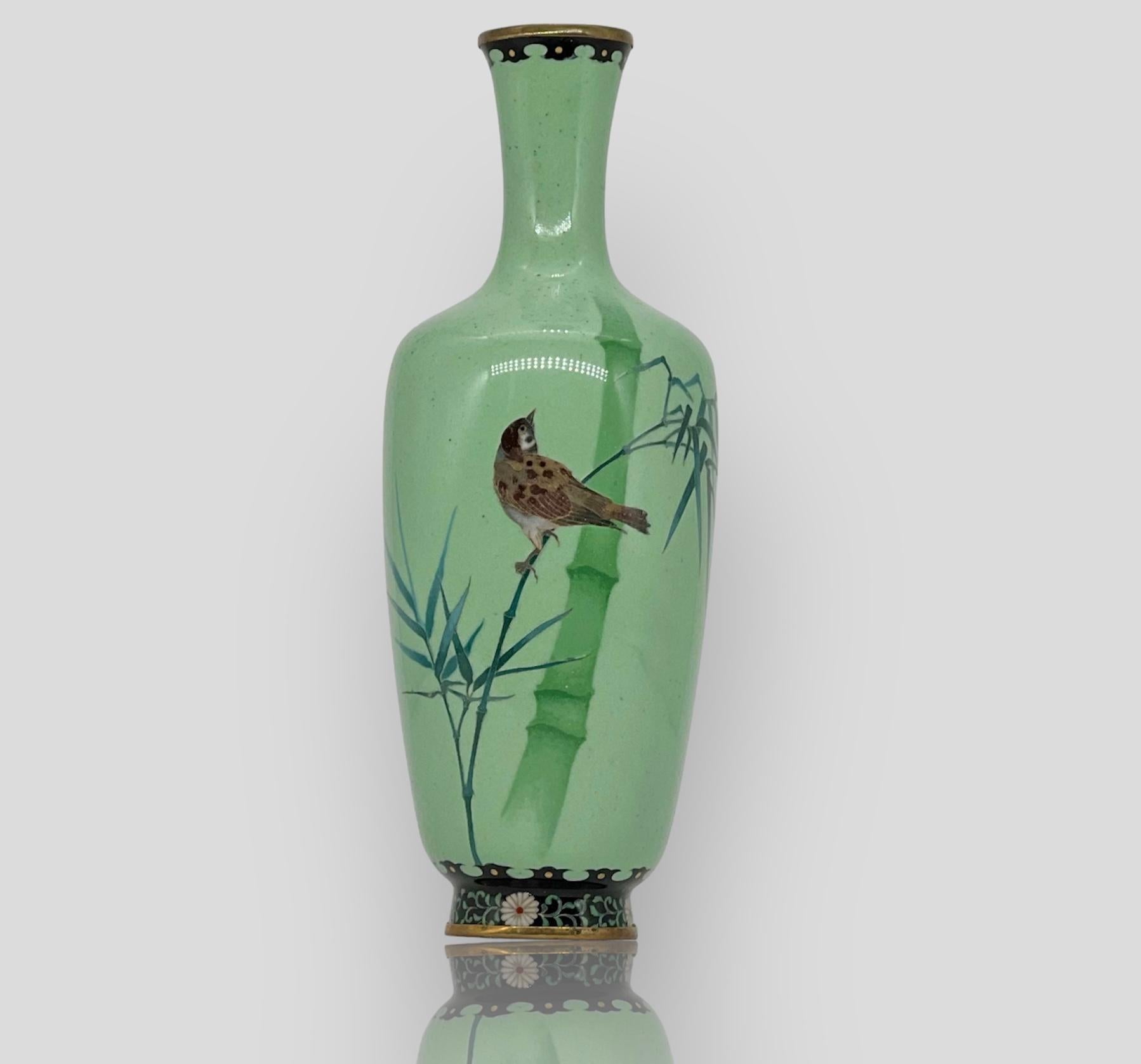 A magnificent Japanese Cloisonne Enamel shouldered vase with a long neck worked in silver wire and wireless technique depicting a two bamboo trees and a bird perched along the branch in the foreground on a pale green ground with a shakudo rim and 