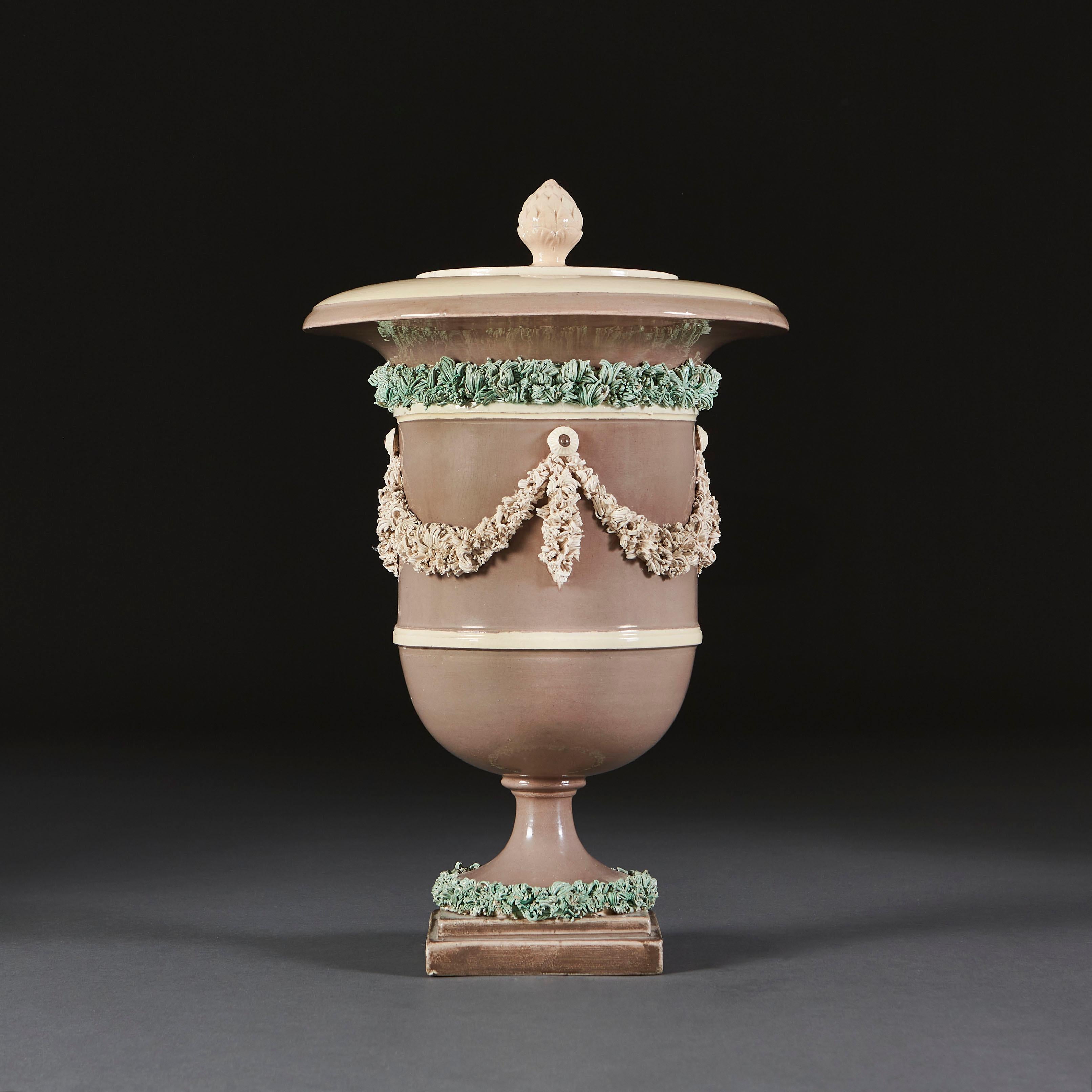 An early nineteenth century neoclassical ice pail modelled in greens and greys with applied decorative swags, removable lid with acorn finial, all supported on a square plinth base.