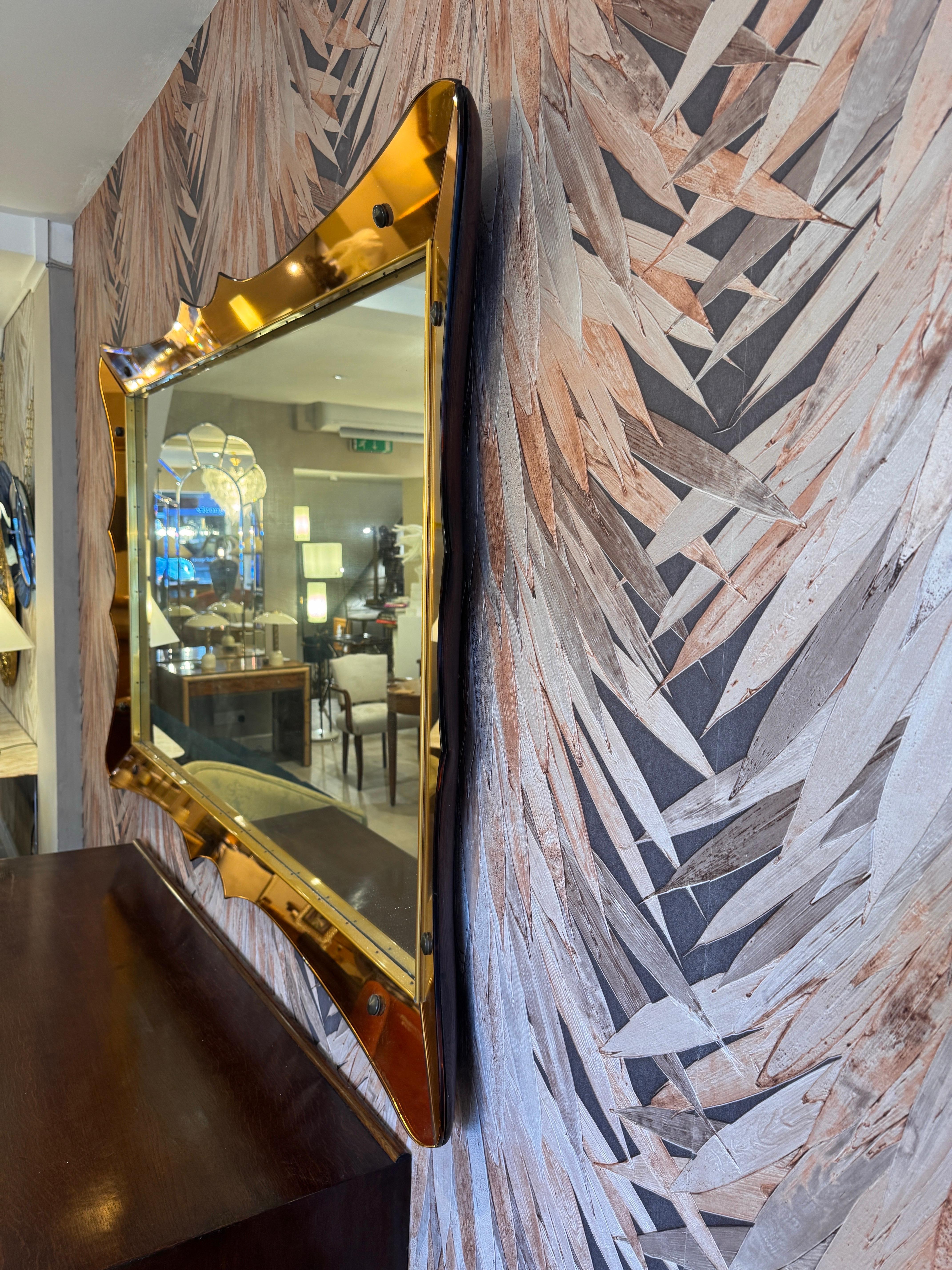 Un grand miroir mural horizontal Cristal Arte, de forme festonnée, avec un magnifique cadre en verre miroir or rose et des connecteurs en laiton. Support épais en bois massif à l'arrière avec crochets muraux métalliques intégrés. 
Le miroir peut