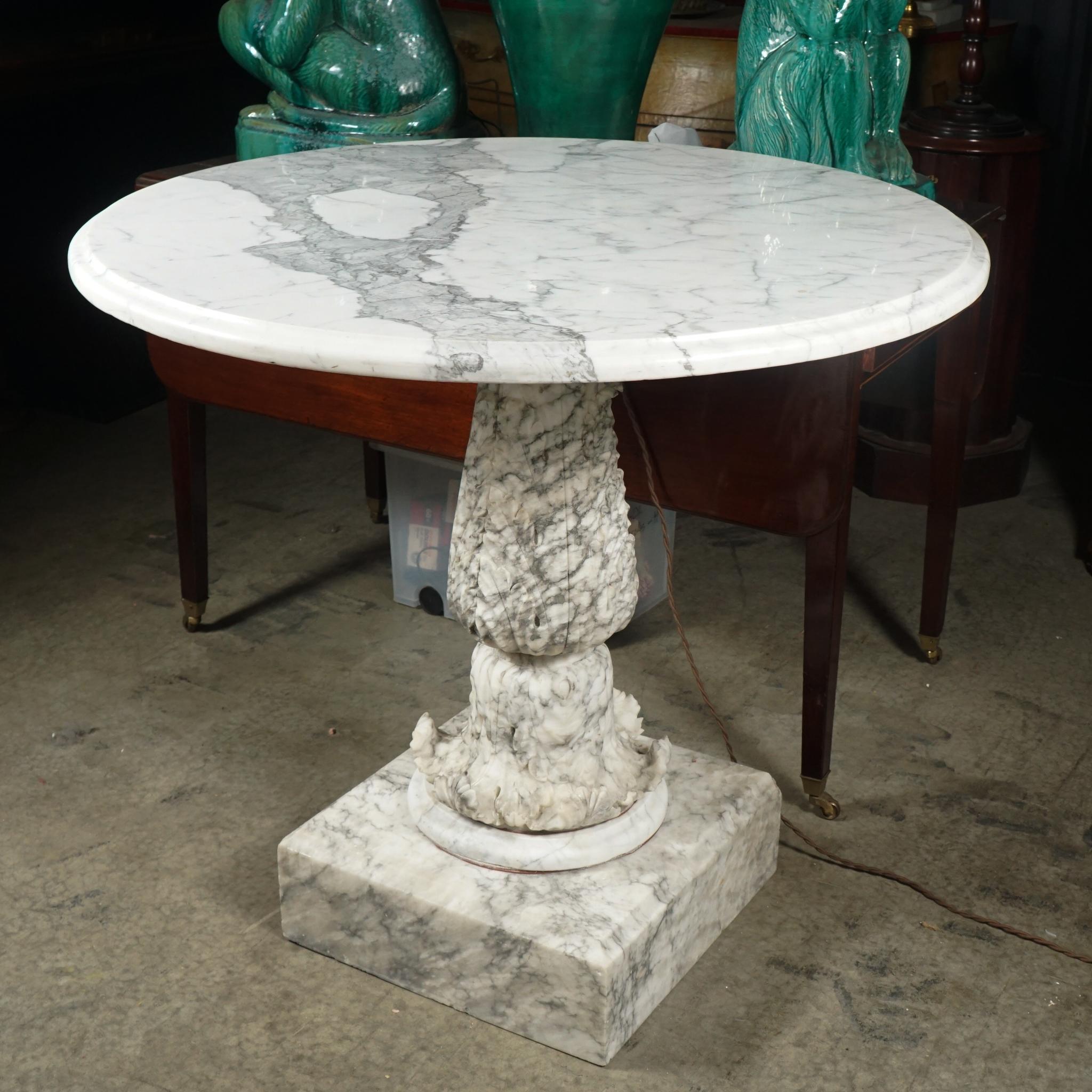 This carved marble center table comes from Italy and was made in the late 19th century. Bought as an outdoor table buy us this could and might have been used at one point as an indoor table. The pedestal carved in one kind of marble that is white