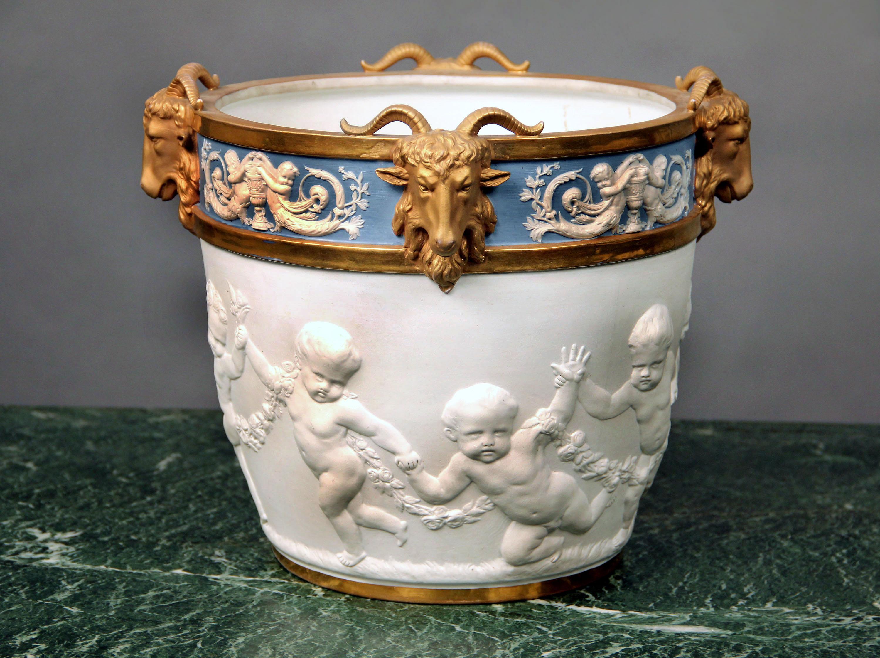 A fine quality late 19th century Dresden parcel-gilt and biscuit porcelain jardinière.

The border moulded with cherubs and applied with rams’ heads above a relief of putti with garlands of flowers.