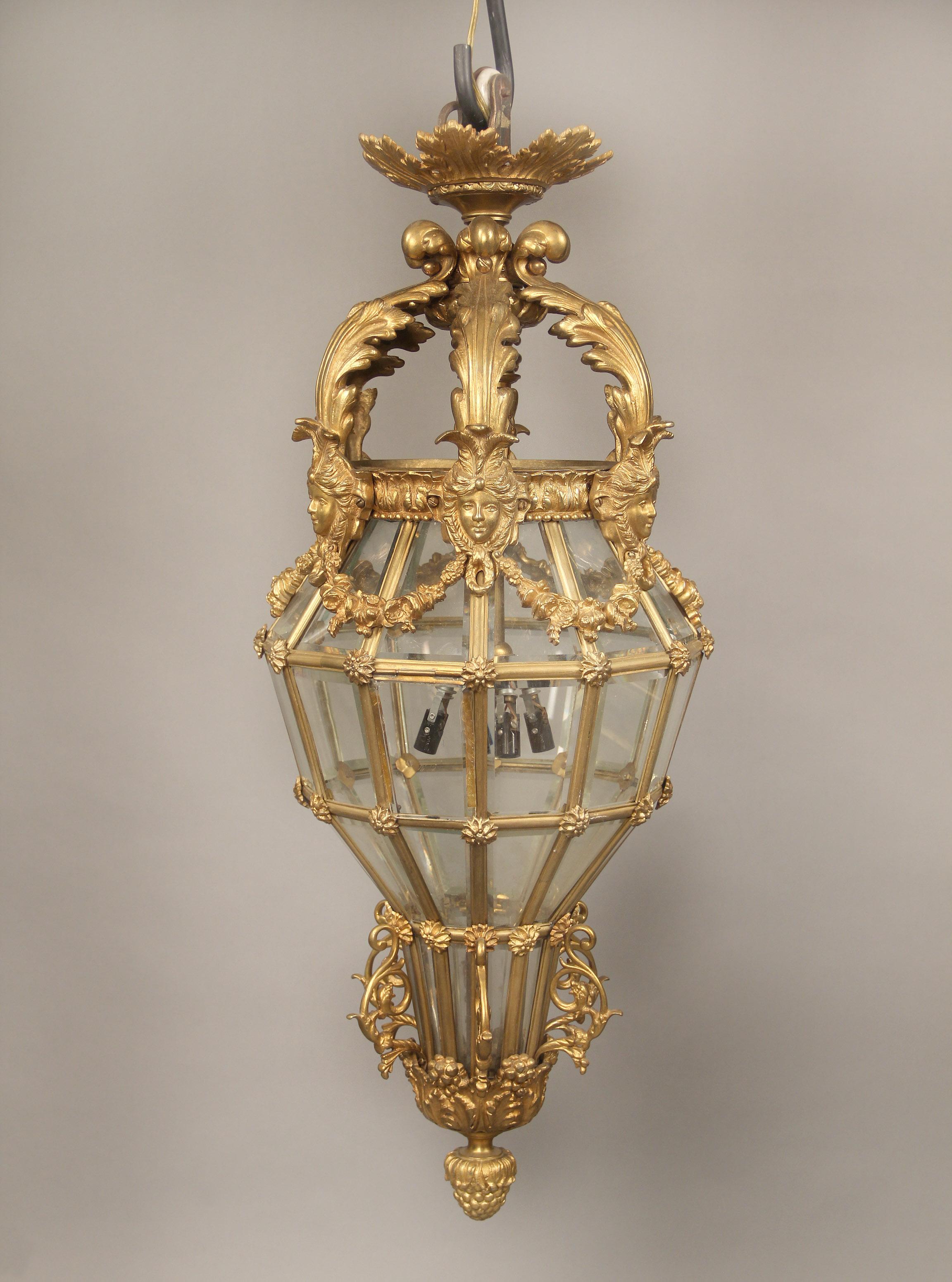 A Fine Late 19th Century Gilt Bronze Figural Lantern

The domed top with six female masks attached with floral swags, above a long shaped body leading to a finished bottom with fruits and an acorn, four interior lights.