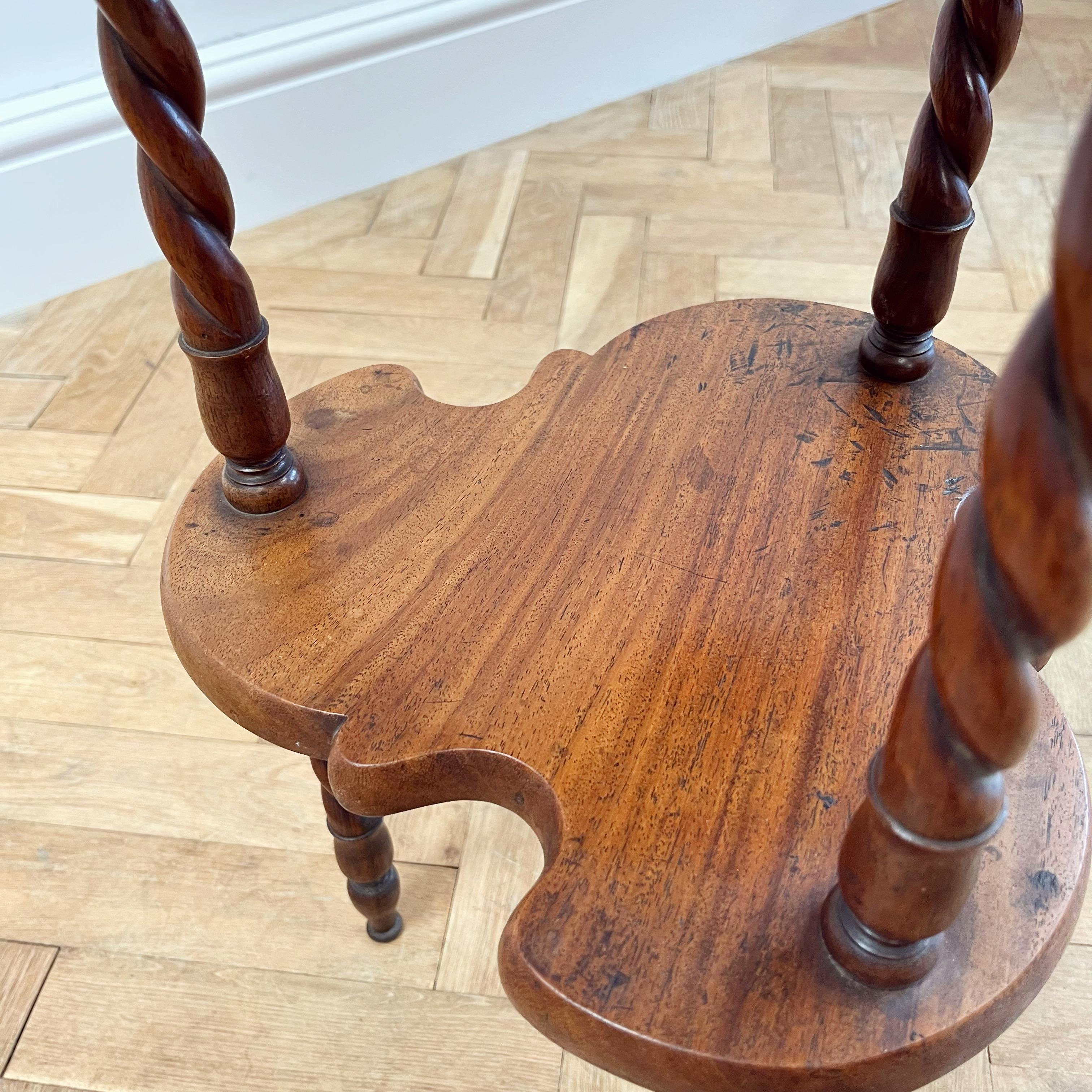 An unusual mahogany two tier side table, the shaped top on three rope twist supports - possible naval connections.

English, Late Nineteenth Century

H 62 x W 42 x D 42 cms 