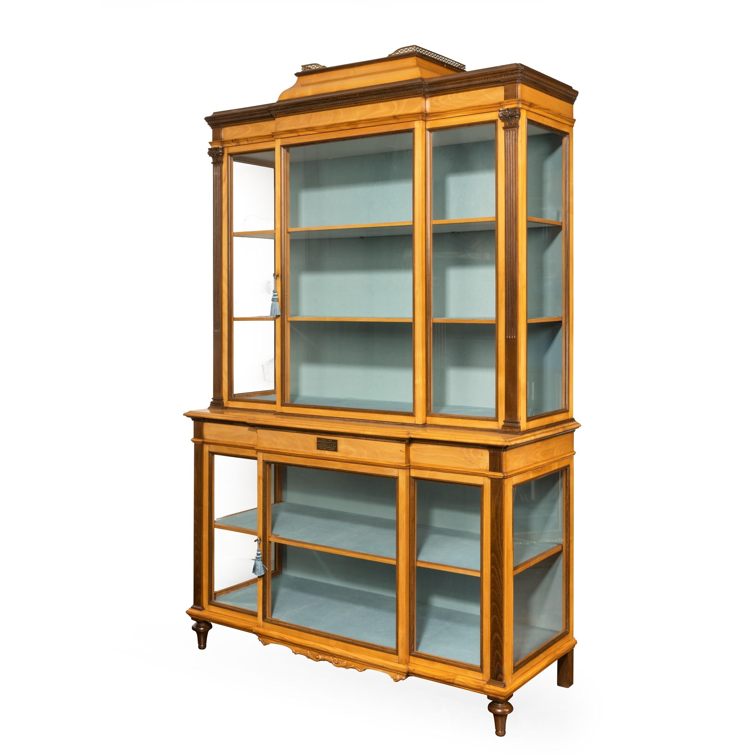 A fine late Victorian Douglas fir, cherry and laburnum display cabinet from Cowden Castle, of glazed breakfront form in two sections, the upper section with a single door and with two shelves with double-re-entrant corners surmounted by a plinth